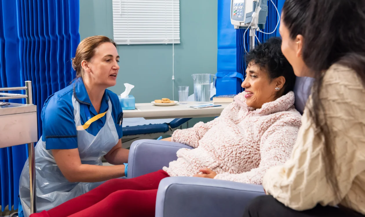 Nurse talking to cancer patient and family members on a hospital ward