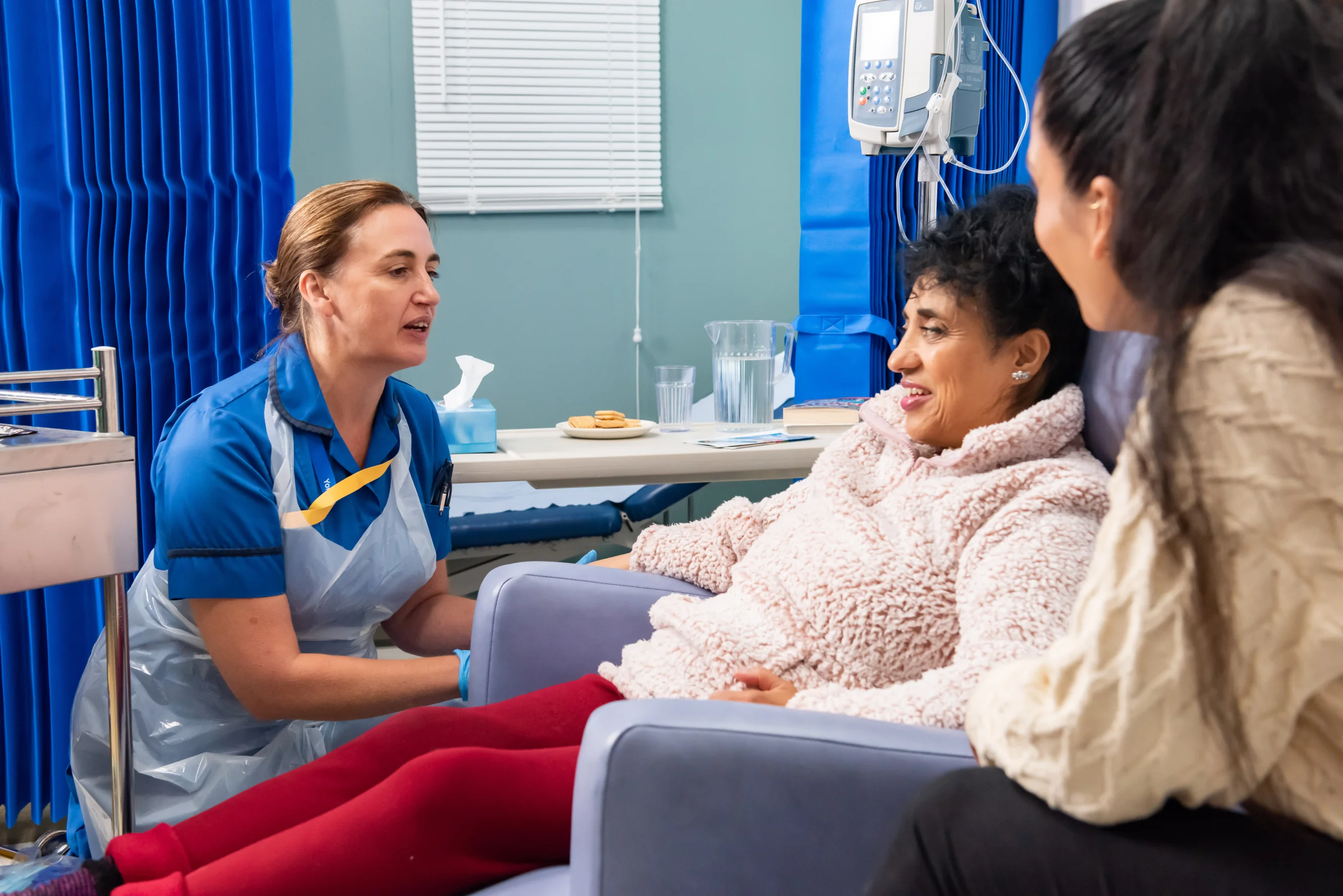 Nurse talking to cancer patient and family members on a hospital ward