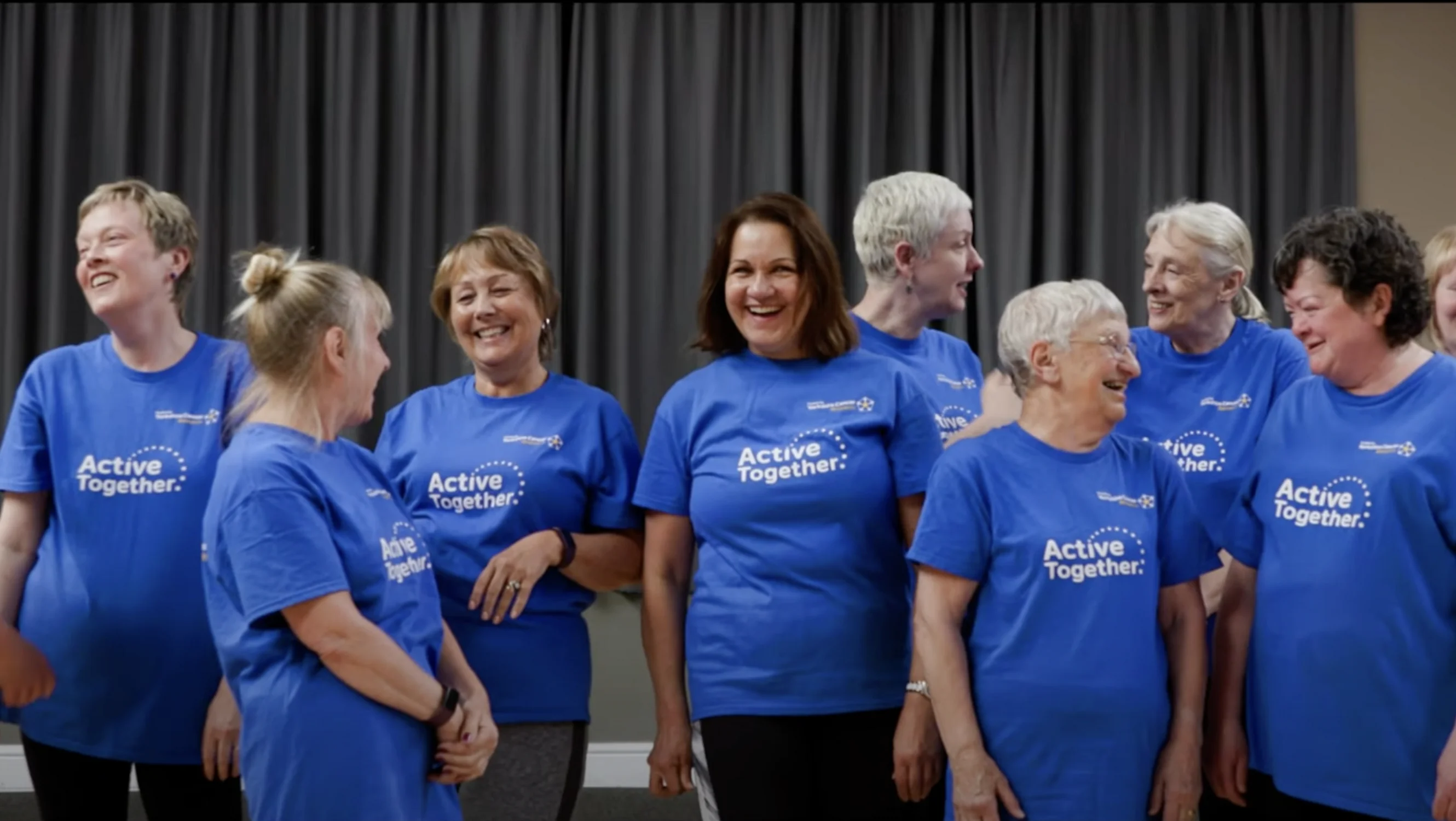 Group of ladies standing and smiling together, wearing Active Together T-shirts