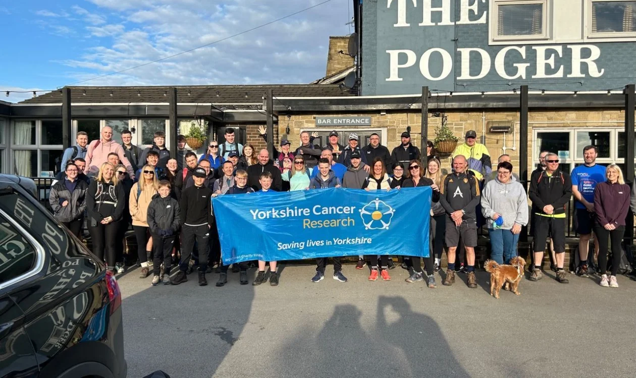 A large group of people pose in front of a public house
