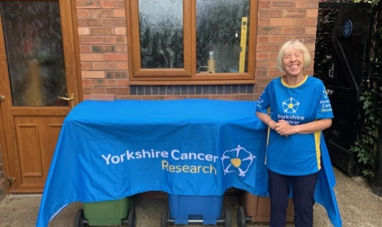 Mary is stood next to a blue Yorkshire Cancer Research banner.