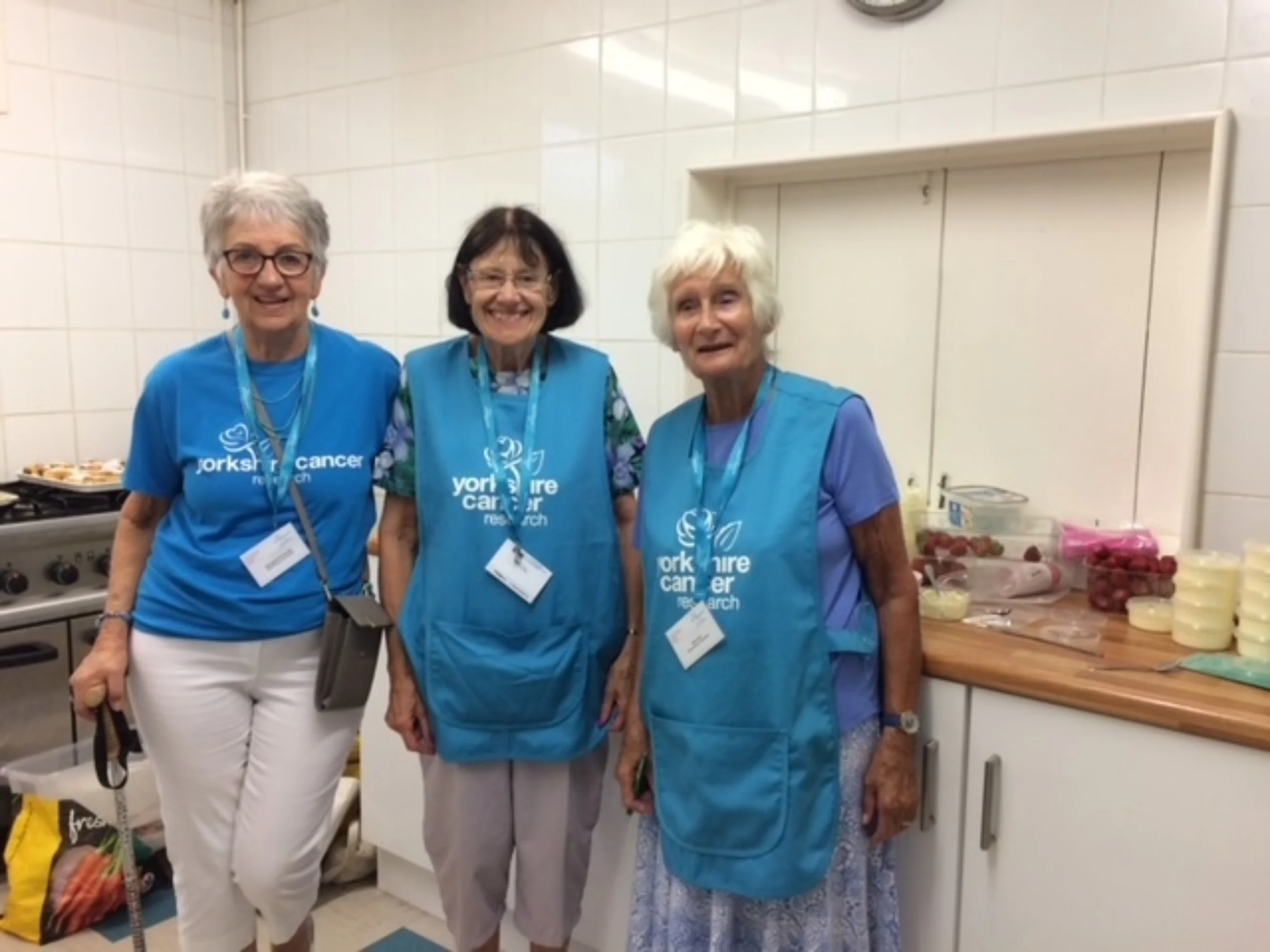 Members of the Wharfedale Local Volunteer Group stood in a kitchen wearing charity branded clothing.