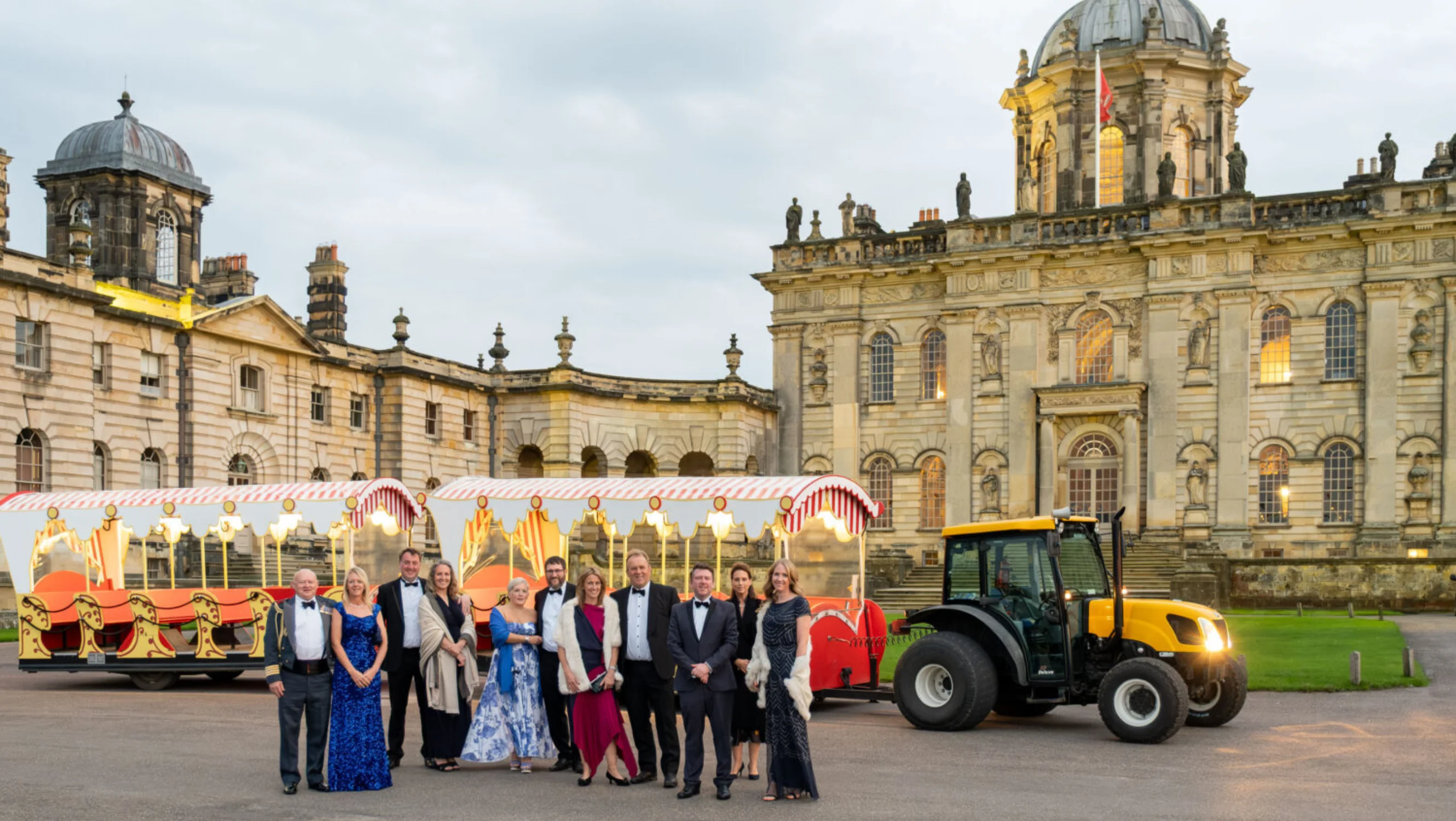 The front of Castle Howard with a tractor pulled train carriage and guests
