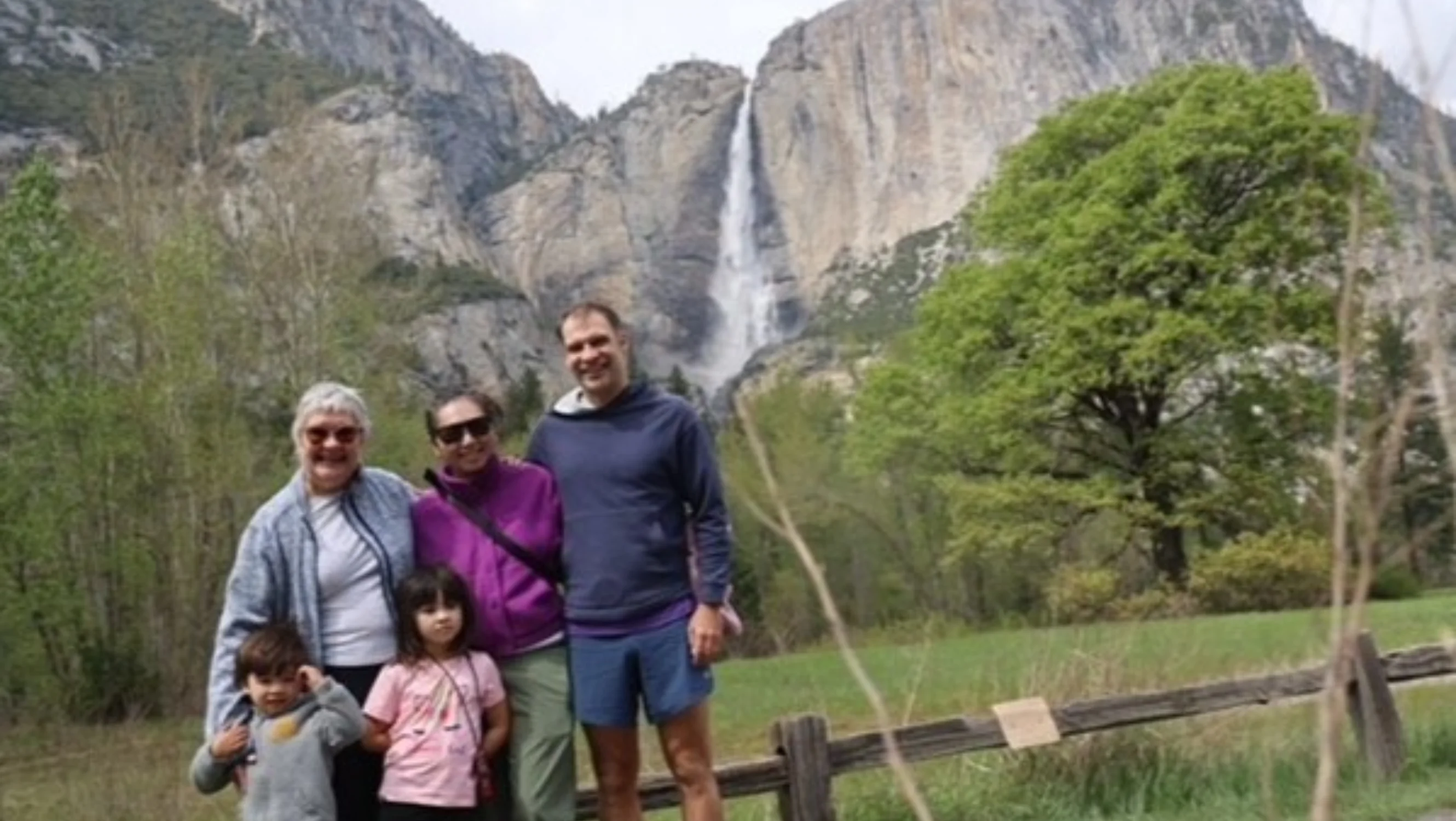 Christine and four members of her family pose for a photograph in front of a large mountain and waterfall.