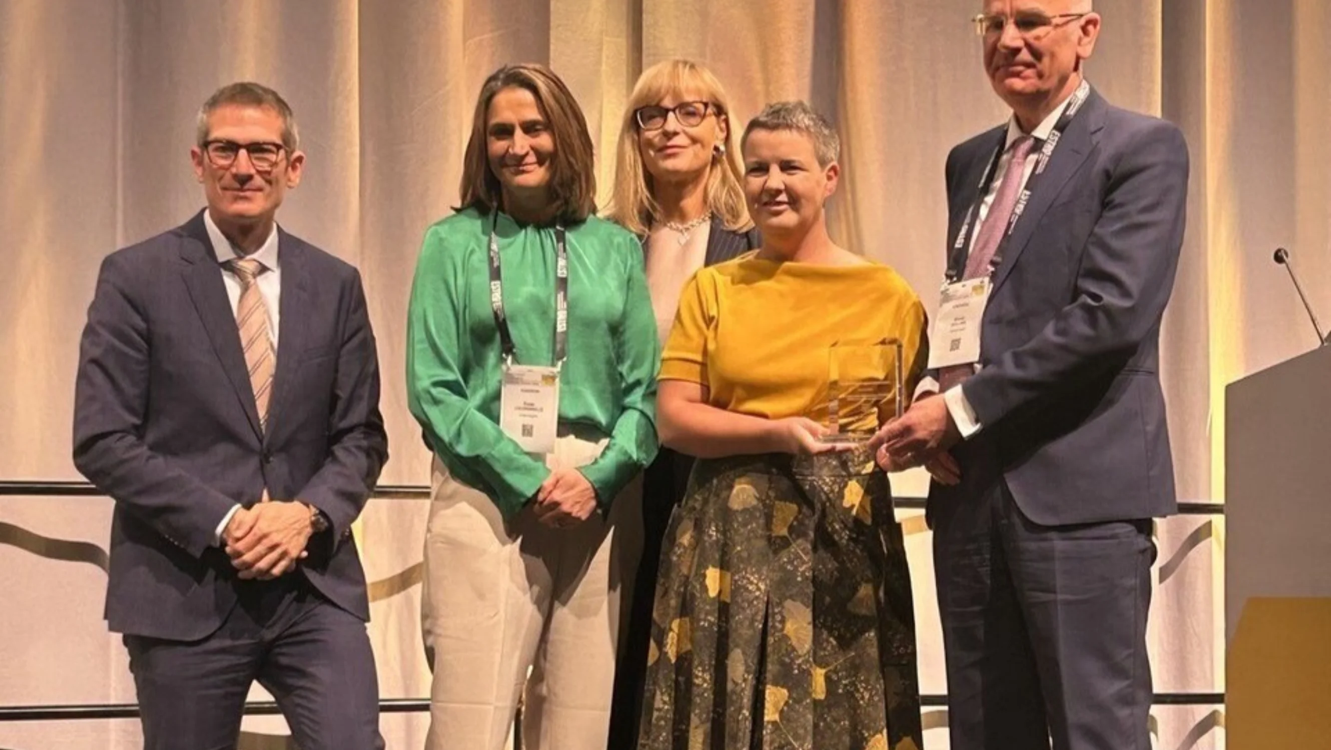 Four people stand on a stage, with one presenting an award to Professor Ane Appelt