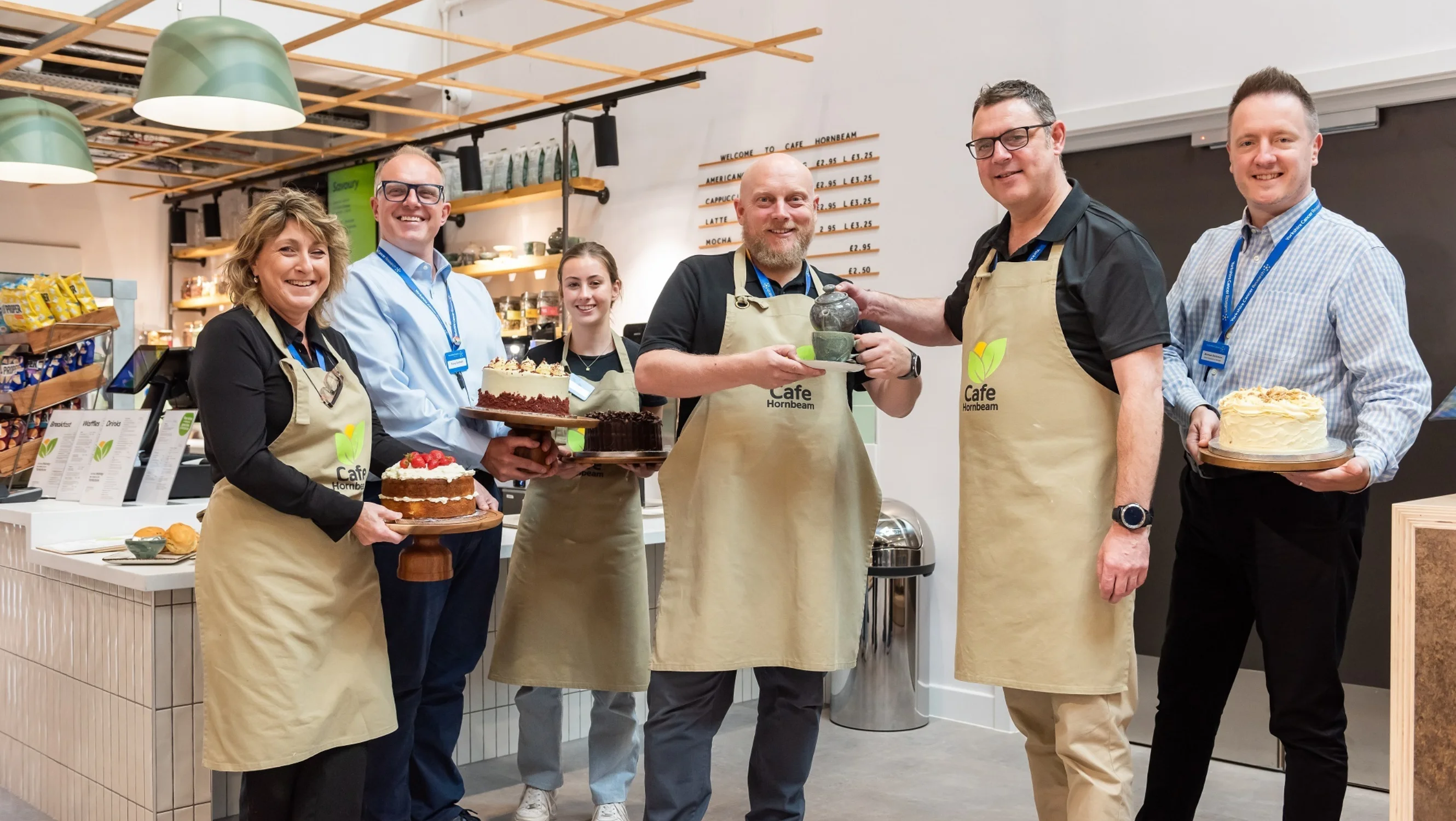 Cafe Hornbeam team standing together, smiling and holding cakes and teapots