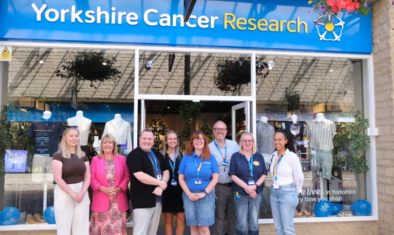 A row of eight people standing outside the Halifax shop smiling at the camera.