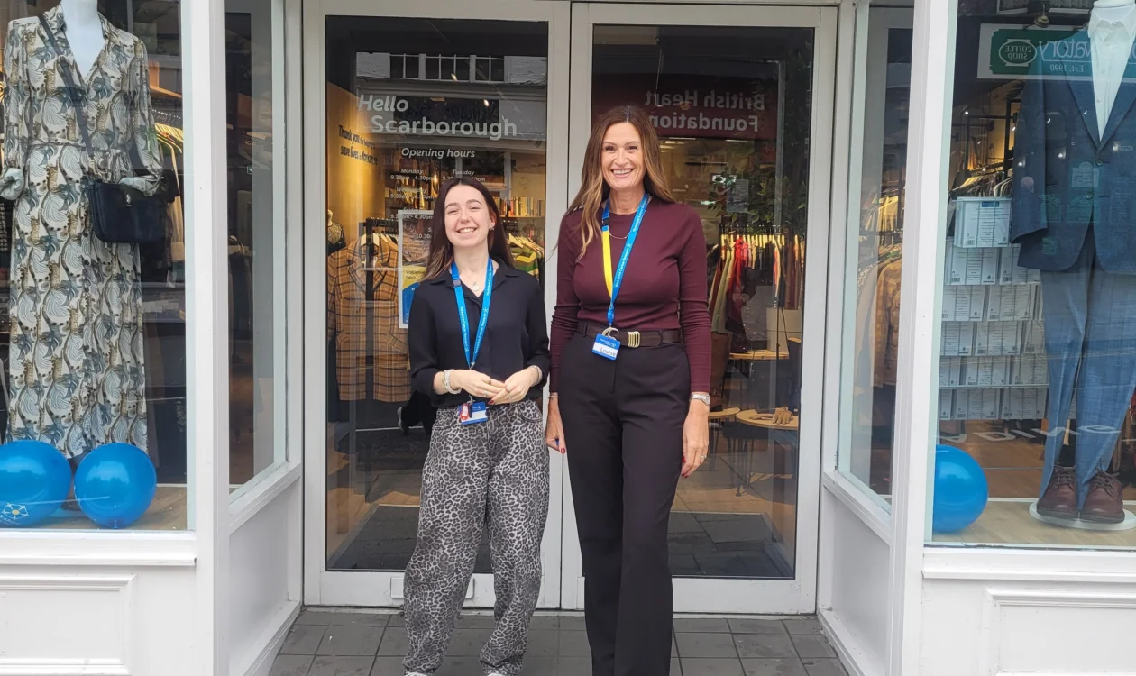 Two ladies standing outside the shop smiling. They both have blue branded "Yorkshire Cancer Research" lanyards on.