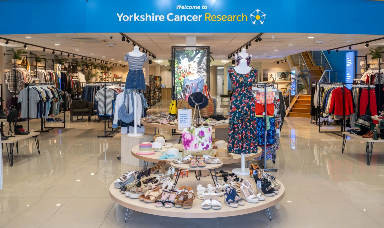 A display of spring/summer women's clothing at the entrance of the shop. There's mannequins wearing floral outfits and in the background there's an expanse of men's and women's clothing displays.