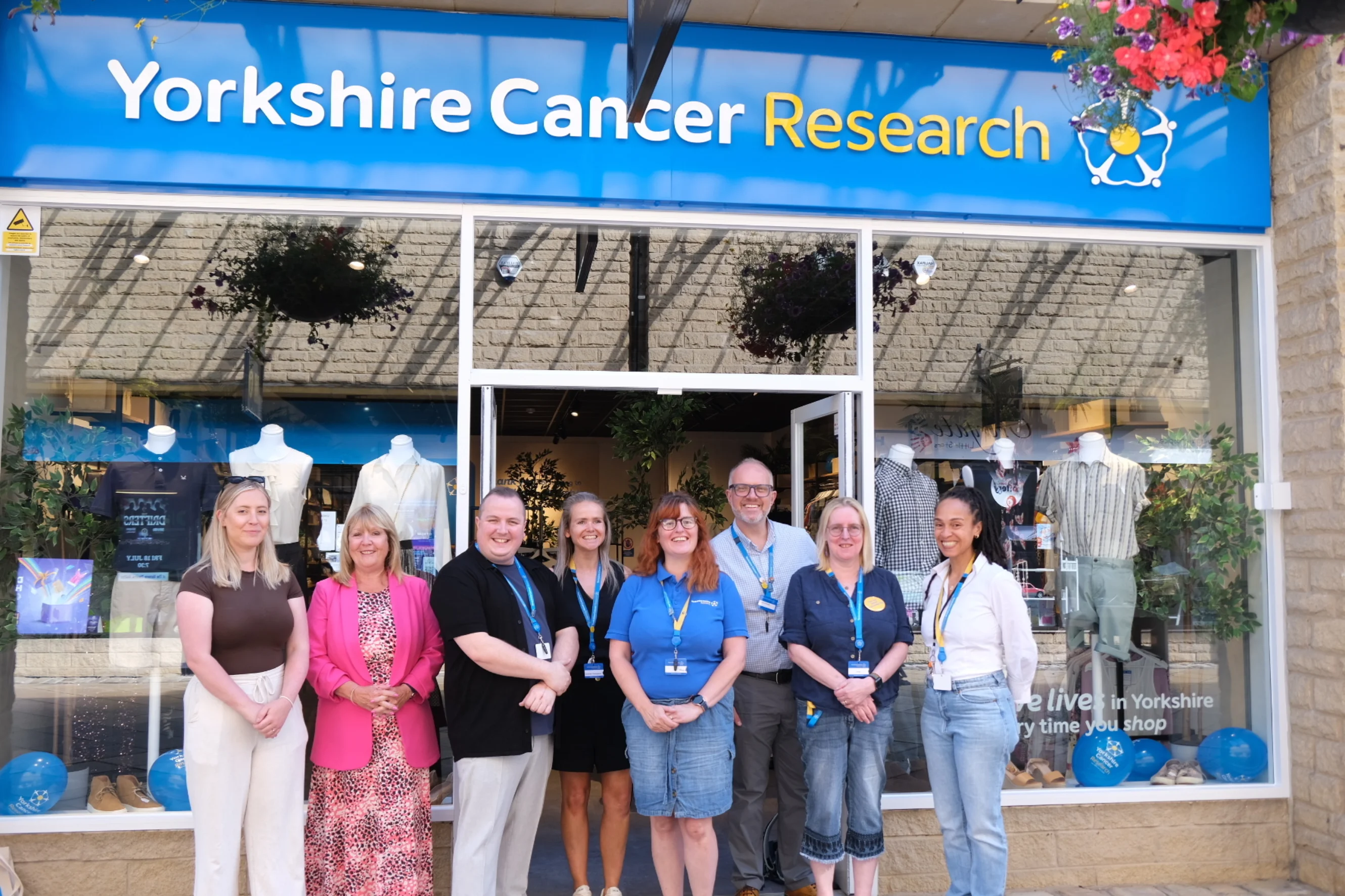 A row of eight people standing outside the Halifax shop smiling at the camera.