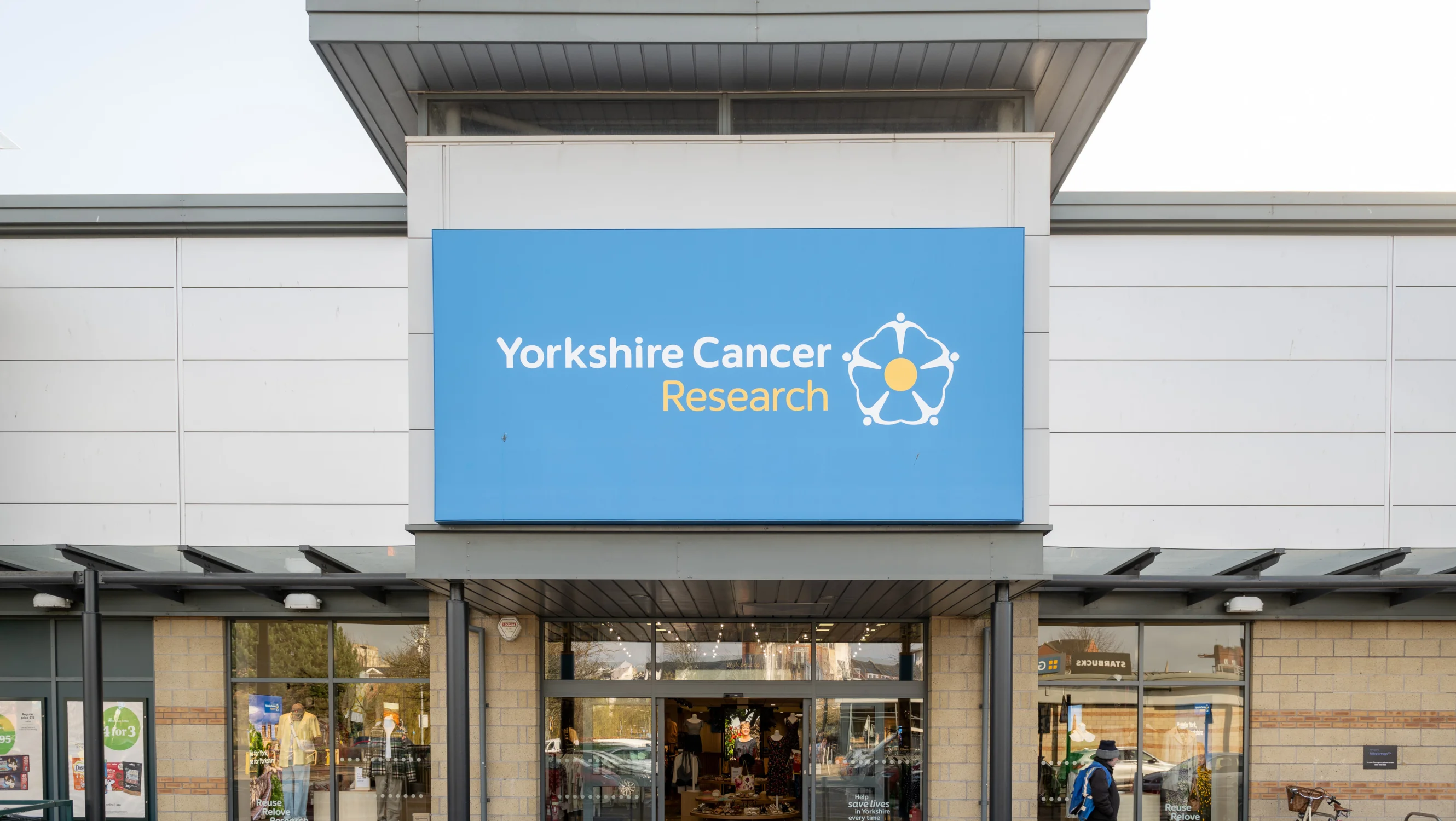 The exterior of the superstore in a retail park. Above the glass doors is a large sign with the charity's logo on it.