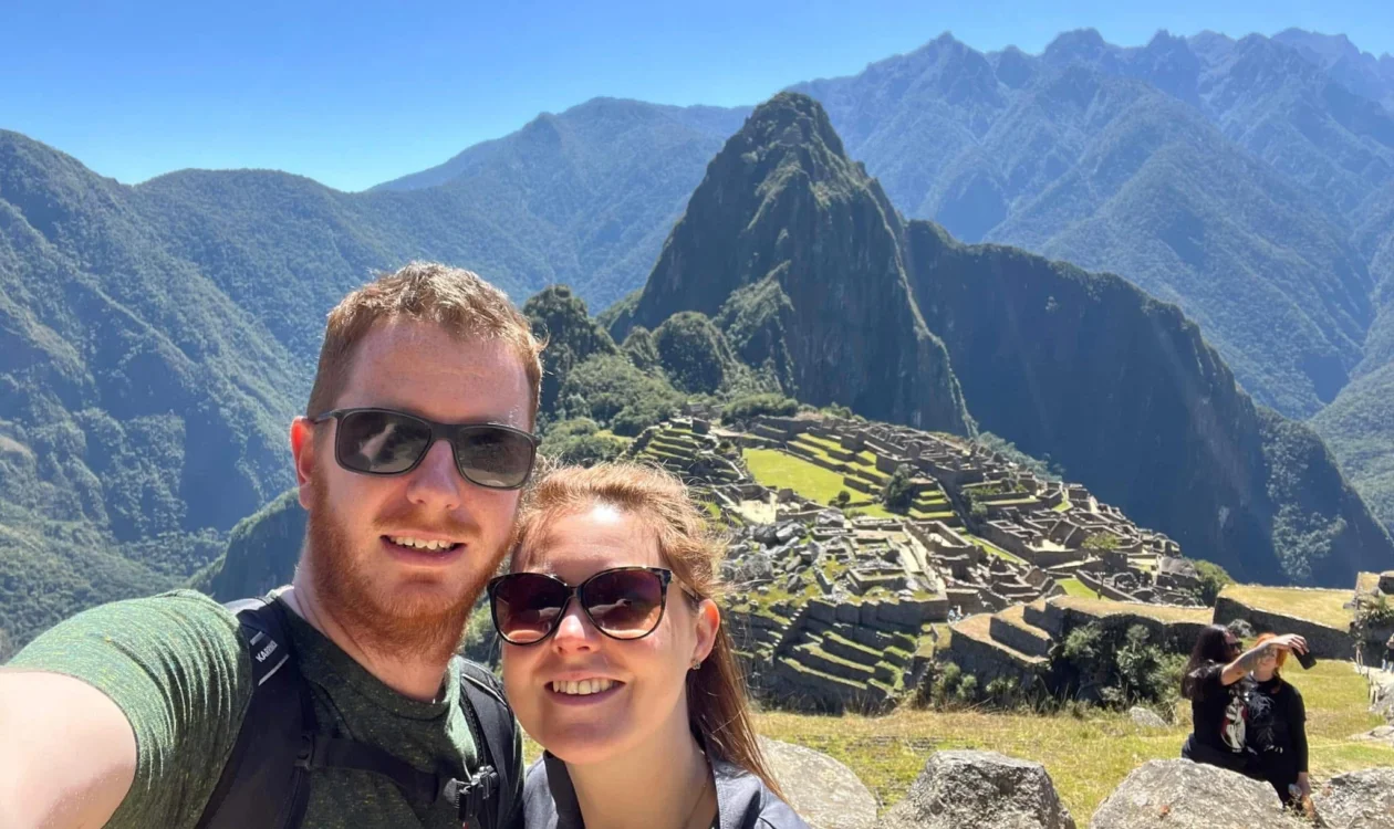 A man and woman take a selfie with Machu Pichu in the background