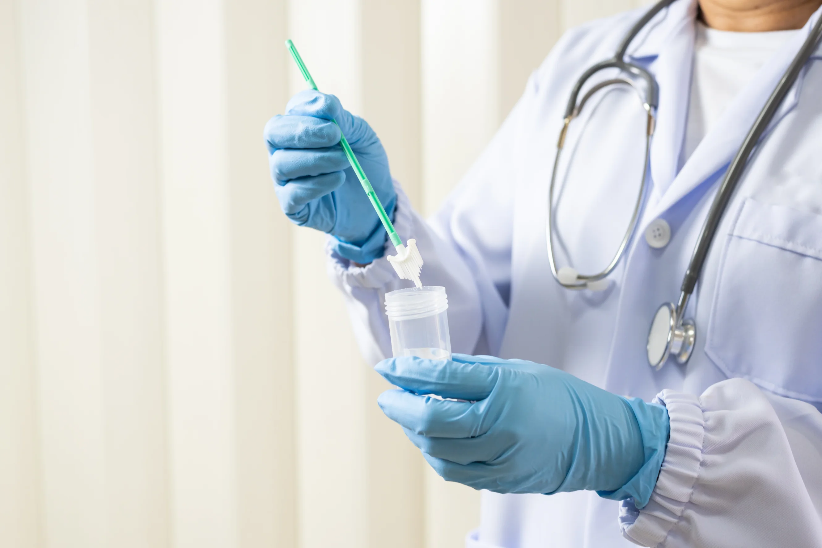 Doctor is holding a cervical screening test kit with gloved hands.