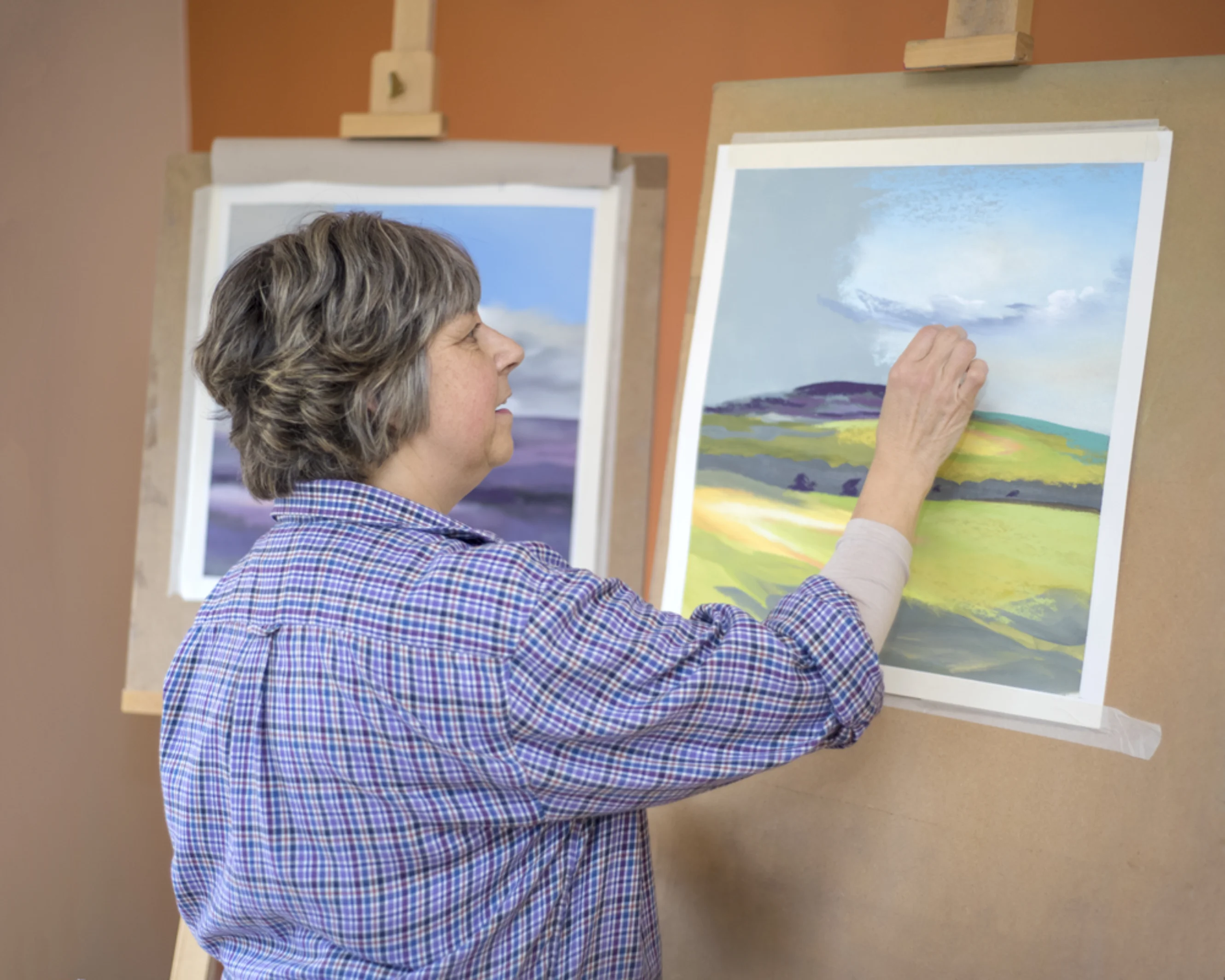 Lucia Smith drawing with oil pastels. She is creating a countryside landscape.