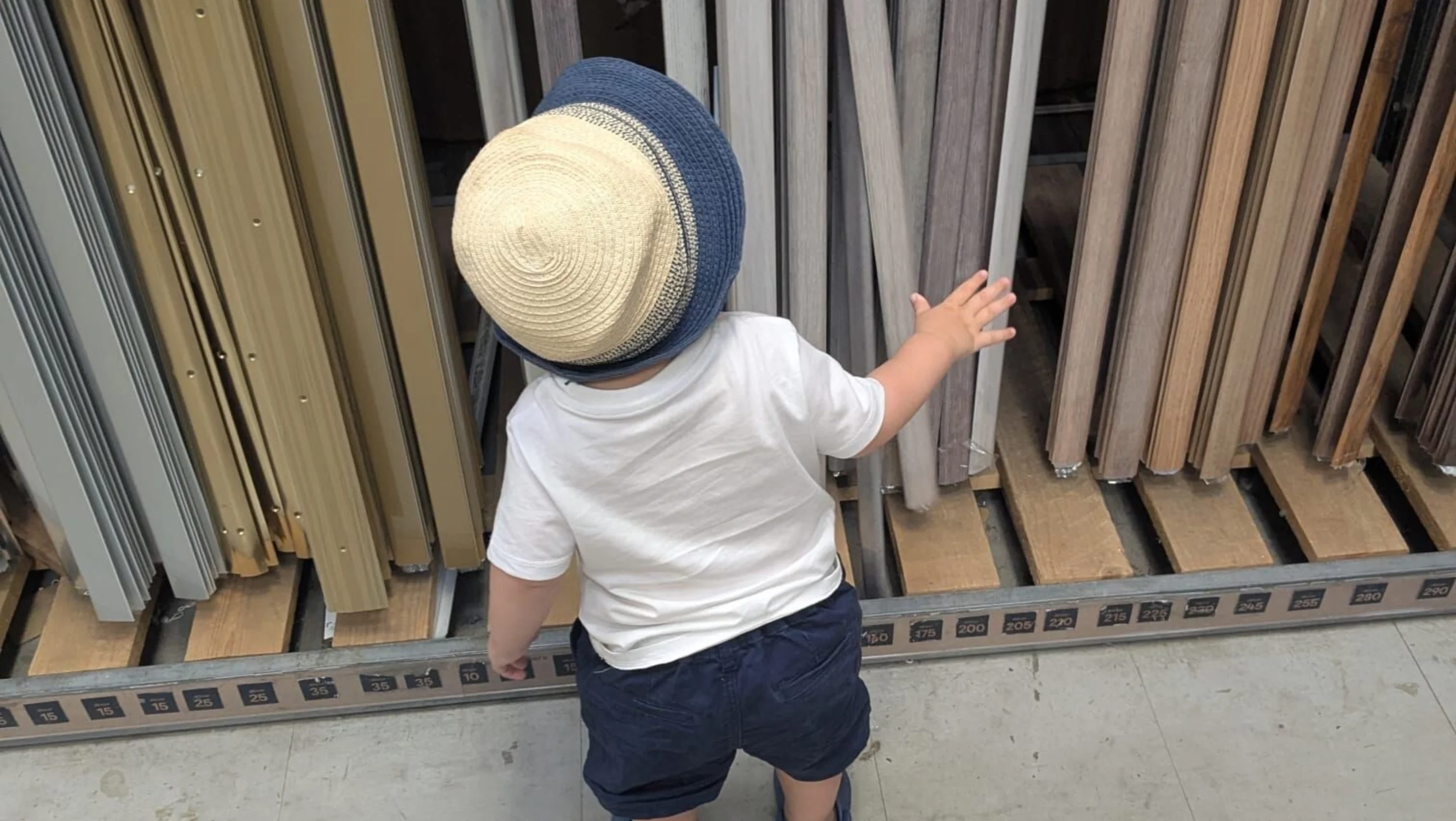 Little boy wearing a summer hat with his back to the camera.