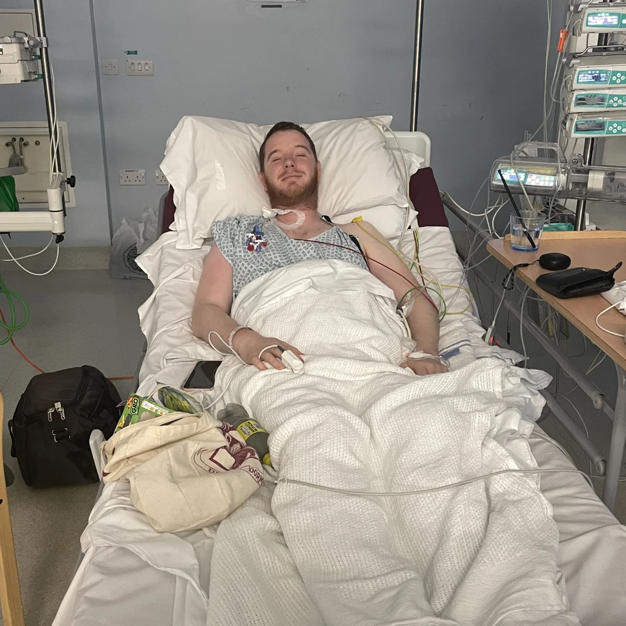 A man lies in a hospital bed looking tired and pale