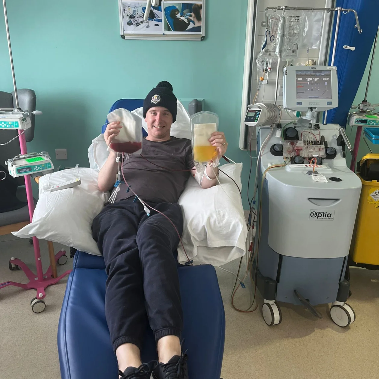 A man receiving treatment on a hospital bed smiles happily