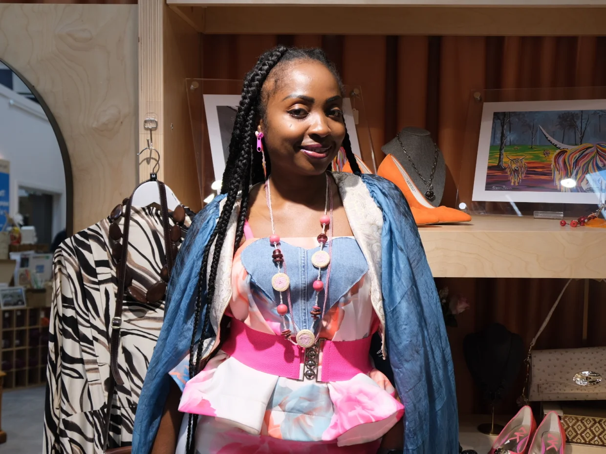 Goodness is standing in front of some shop shelves smiling at the camera