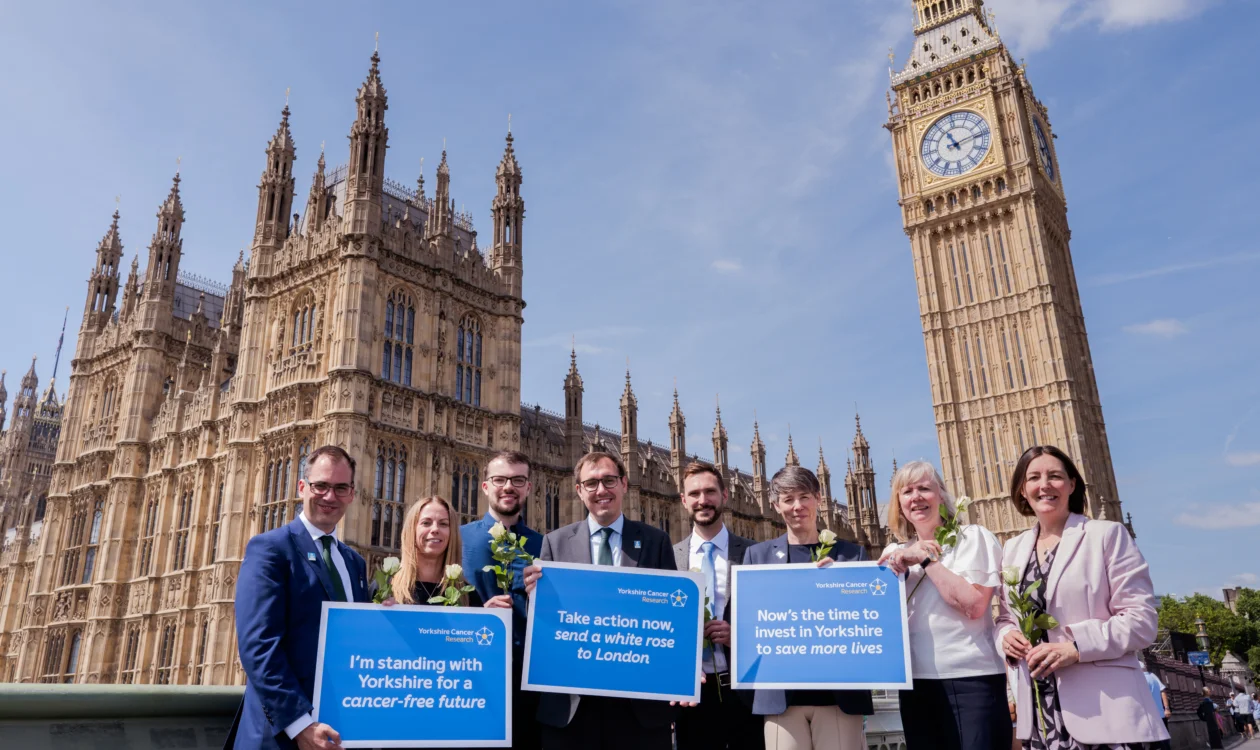 Cancer researchers, people affected by cancer, charity representatives and supporting politicians standing outside of Parliament