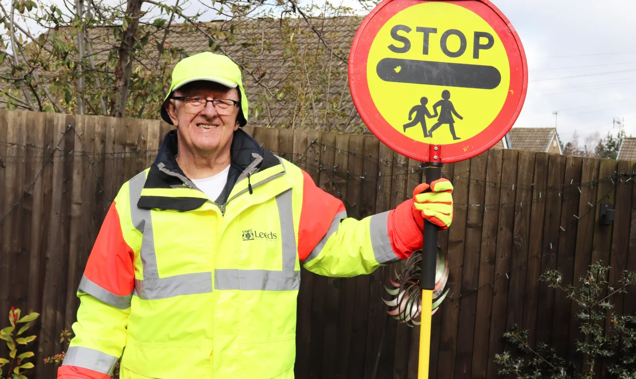 Ernest standing in his lollypop man uniform with a stop sign