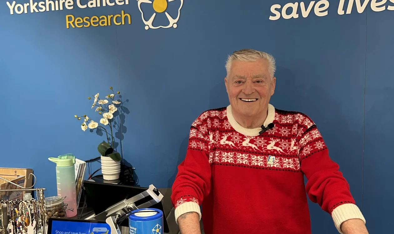 Ian Hepburn in his festive jumper at the till of the Yorkshire Cancer Research shop in Ripon
