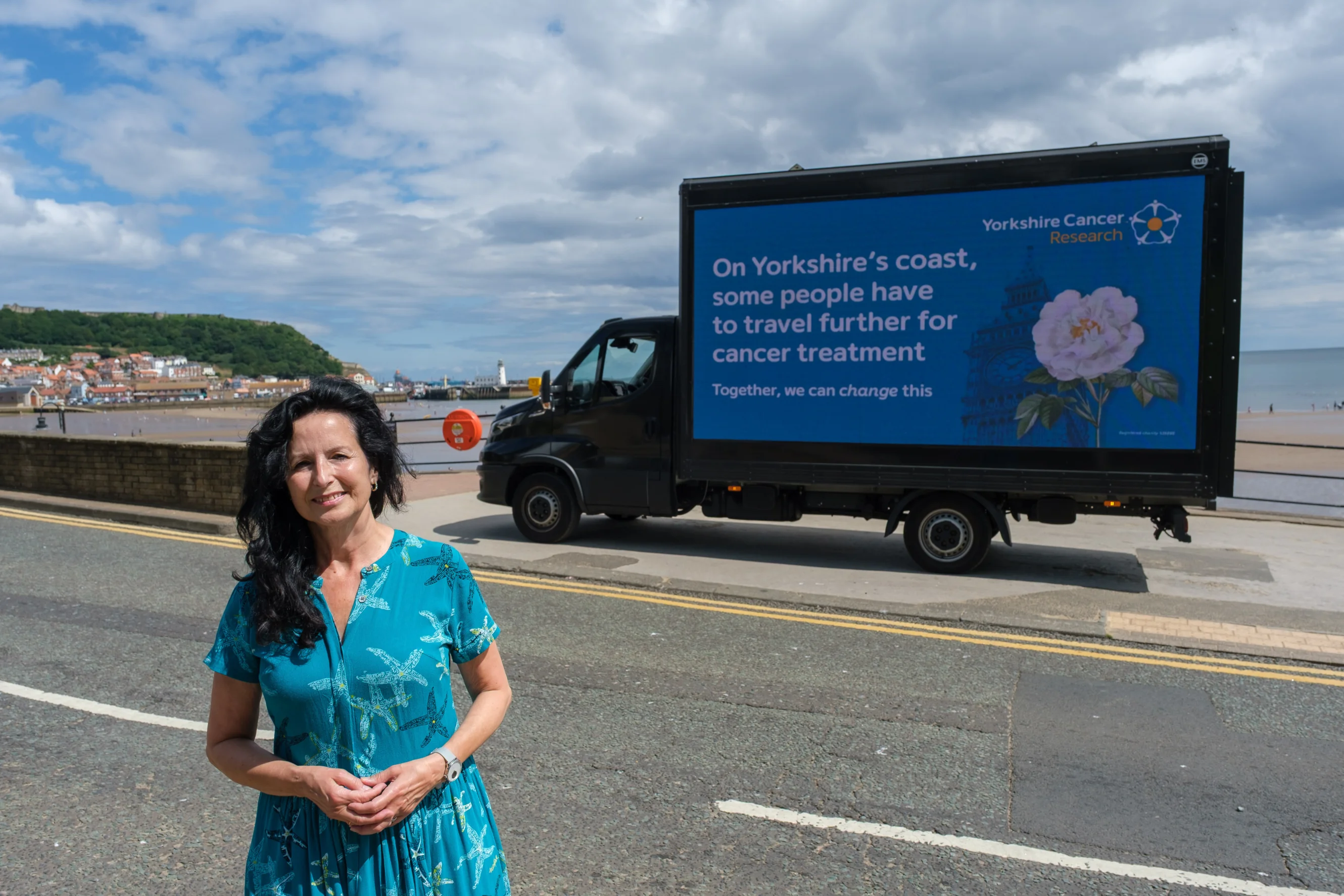 A lady in a sundress stands on Scarborough beach front