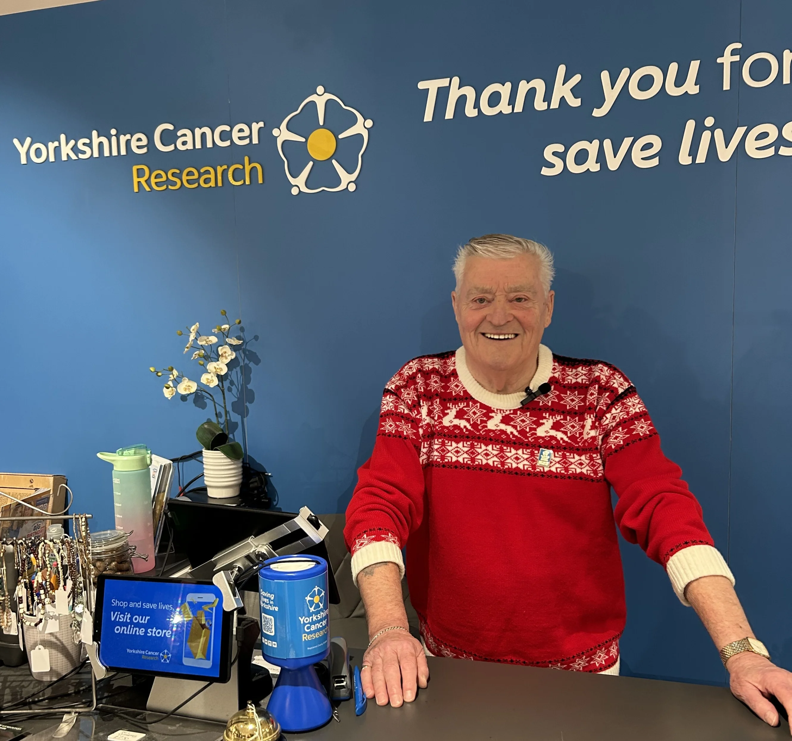 Ian Hepburn in his festive jumper at the till of the Yorkshire Cancer Research shop in Ripon