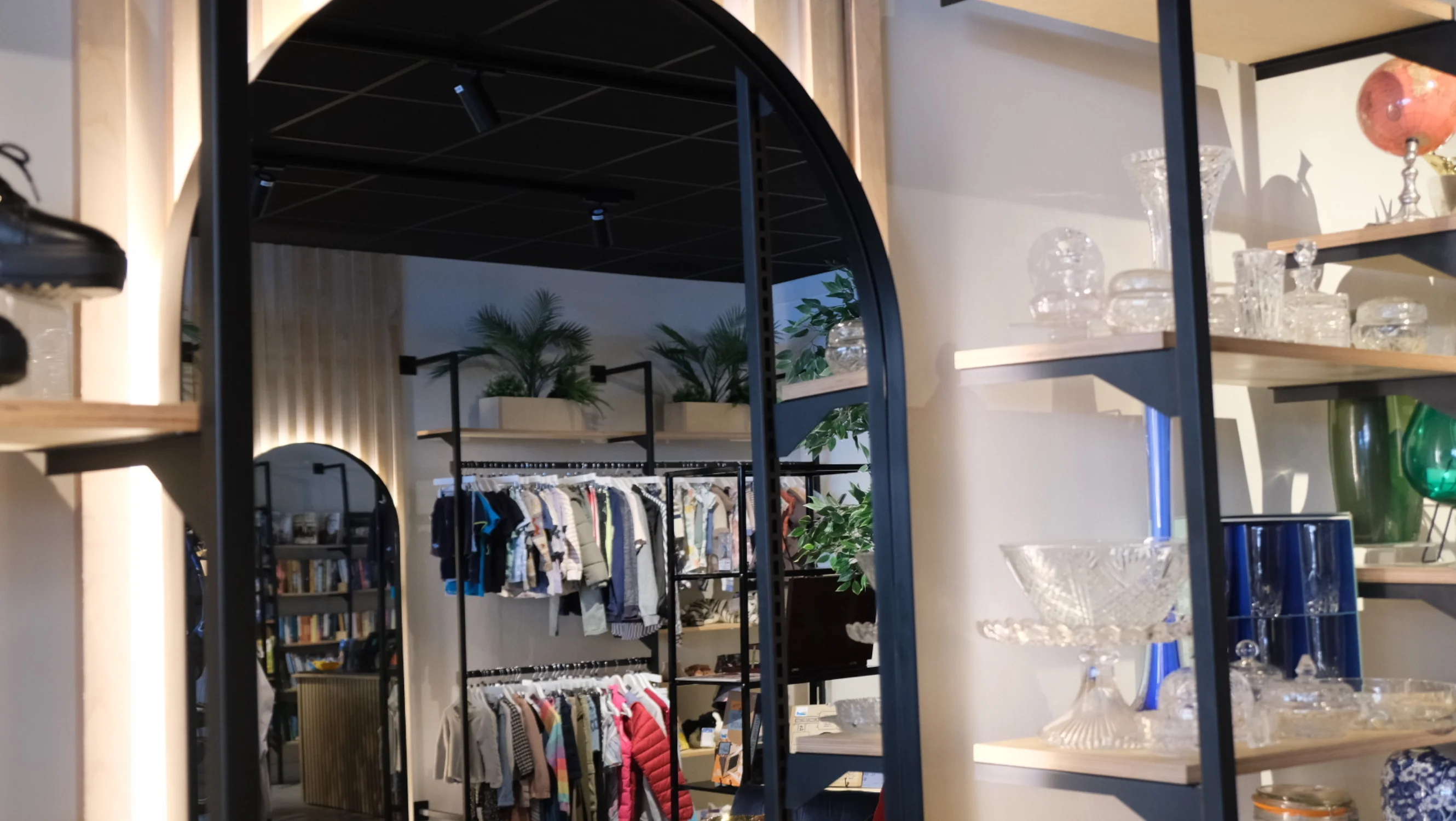 Image of an arch mirror in the shop. In the reflection you can see rails of clothing displayed in the shop.
