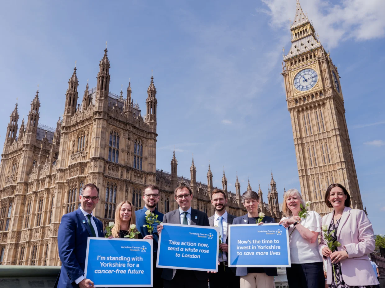 Cancer researchers, people affected by cancer, charity representatives and supporting politicians standing outside of Parliament