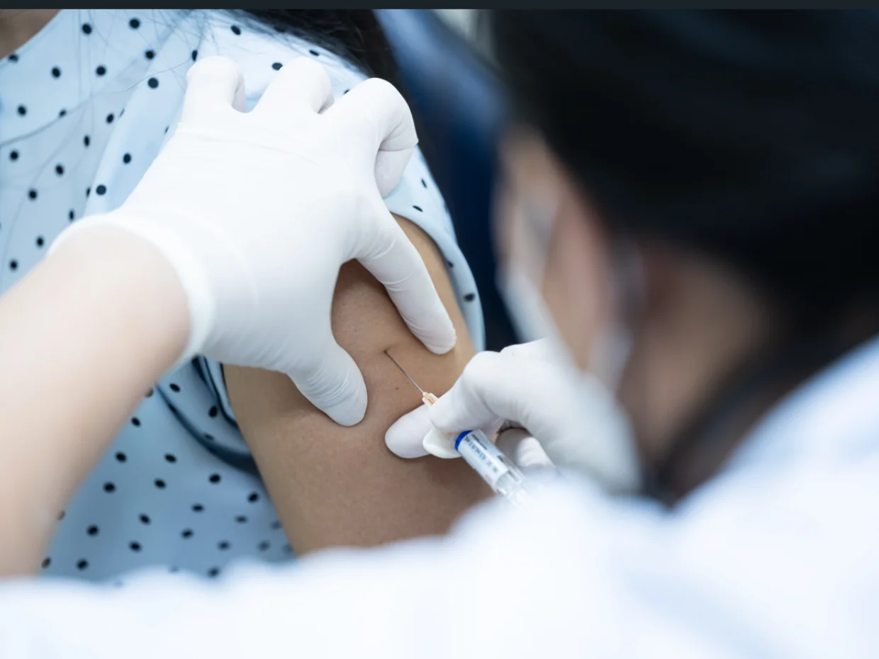 A healthcare professional delivering a vaccine into someone's arm