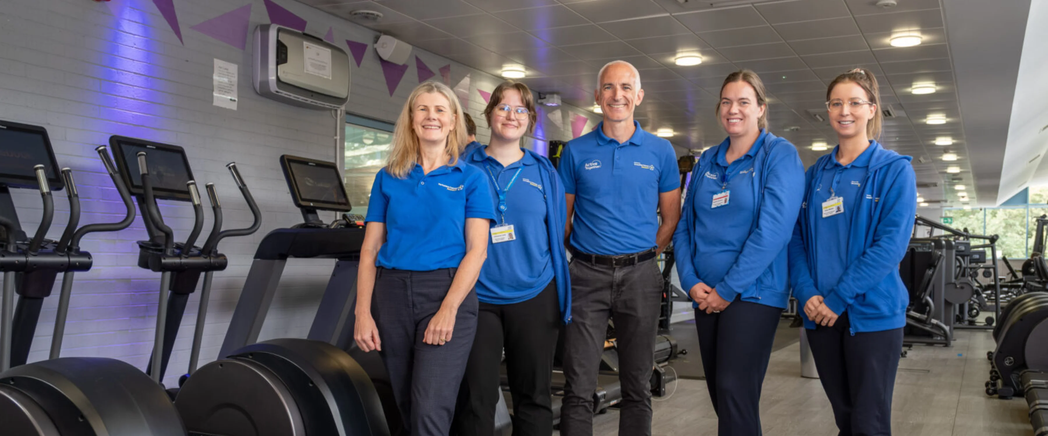 A group of people all dressed in blue standing in a gym