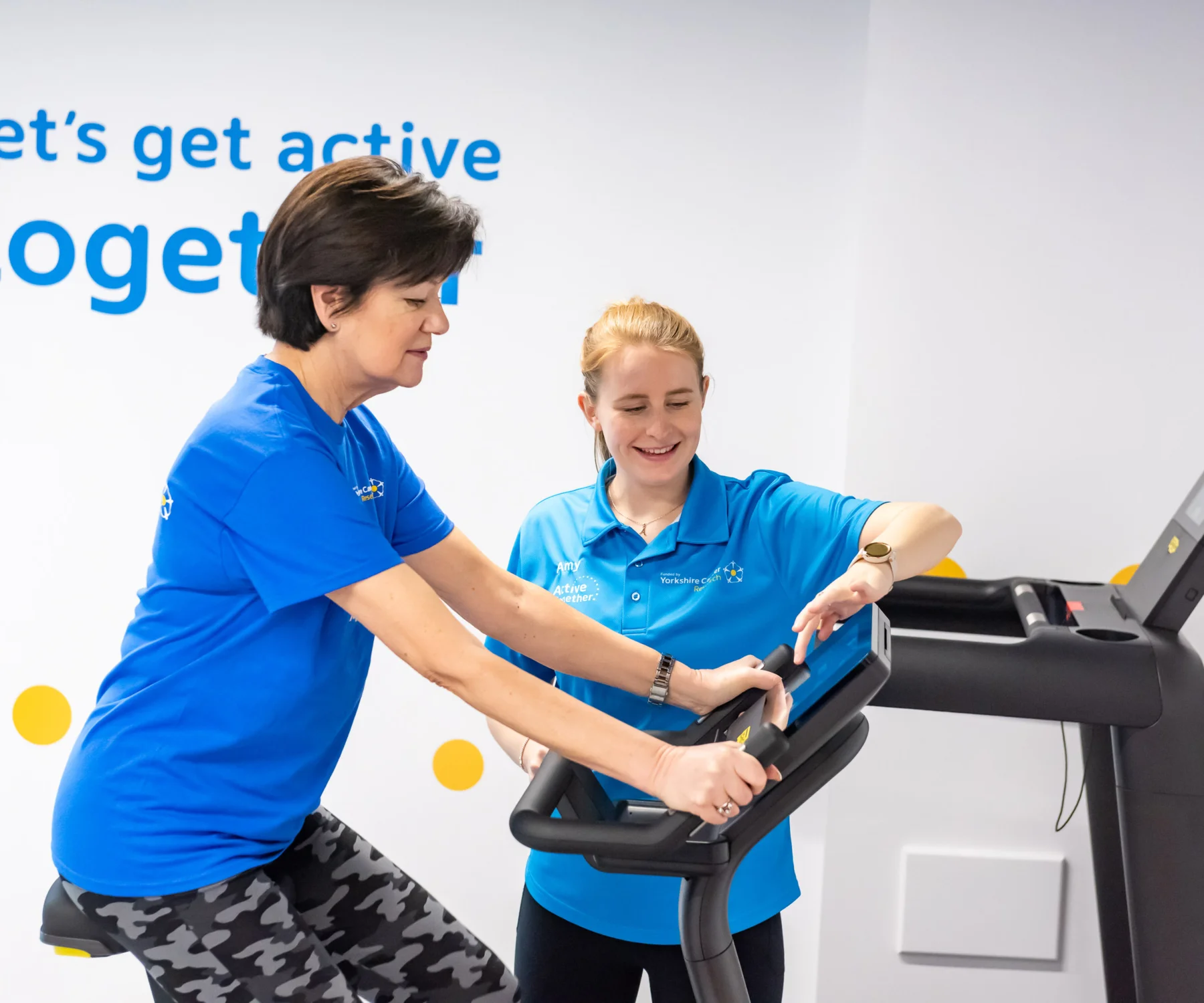 A woman on an indoor bike with a fitness instructor