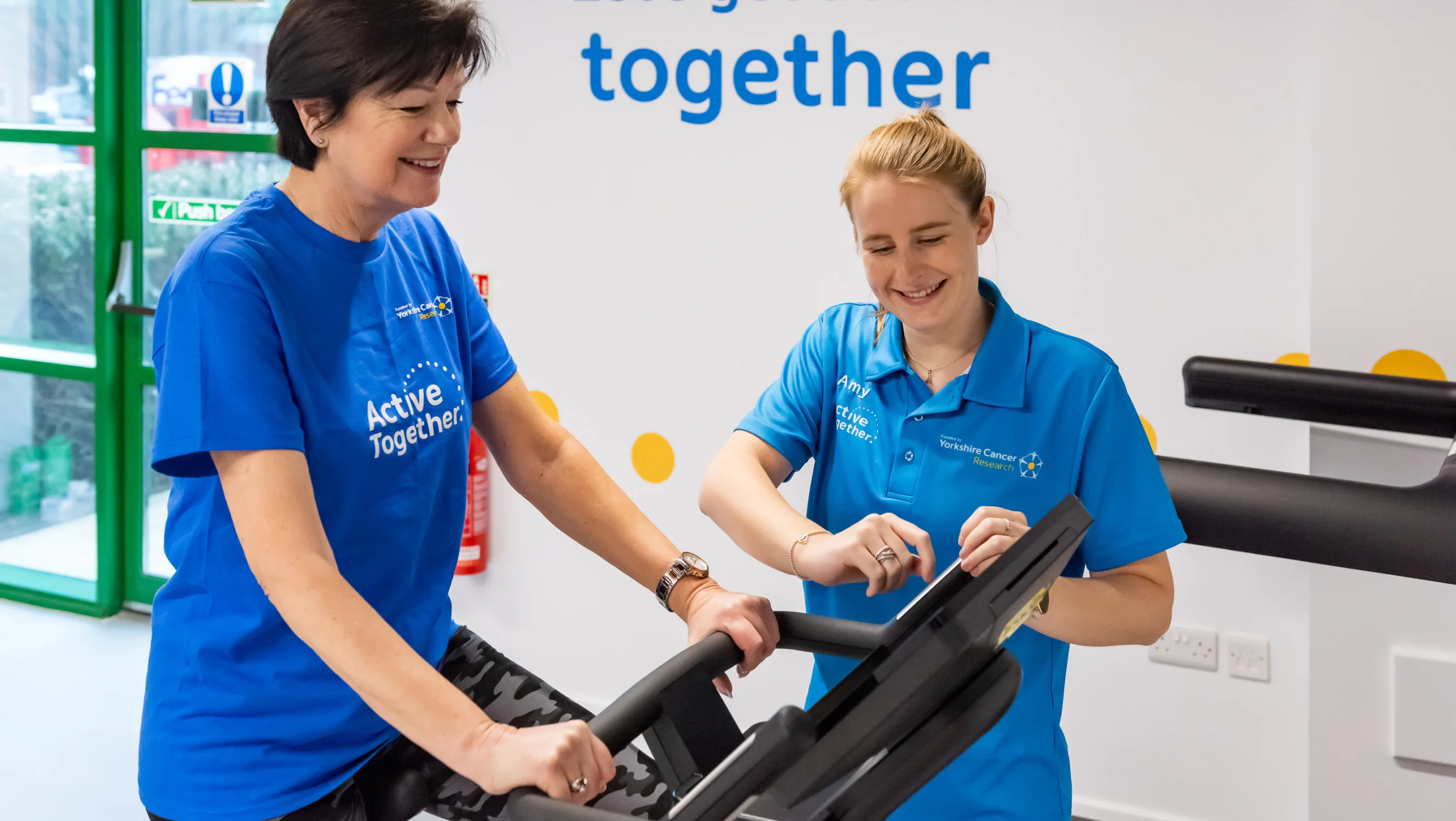 A woman on an indoor bike with a fitness instructor
