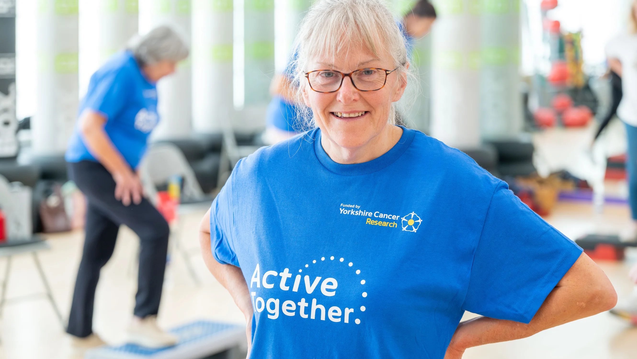 A woman in a blue t-shirt standing in a gym studio