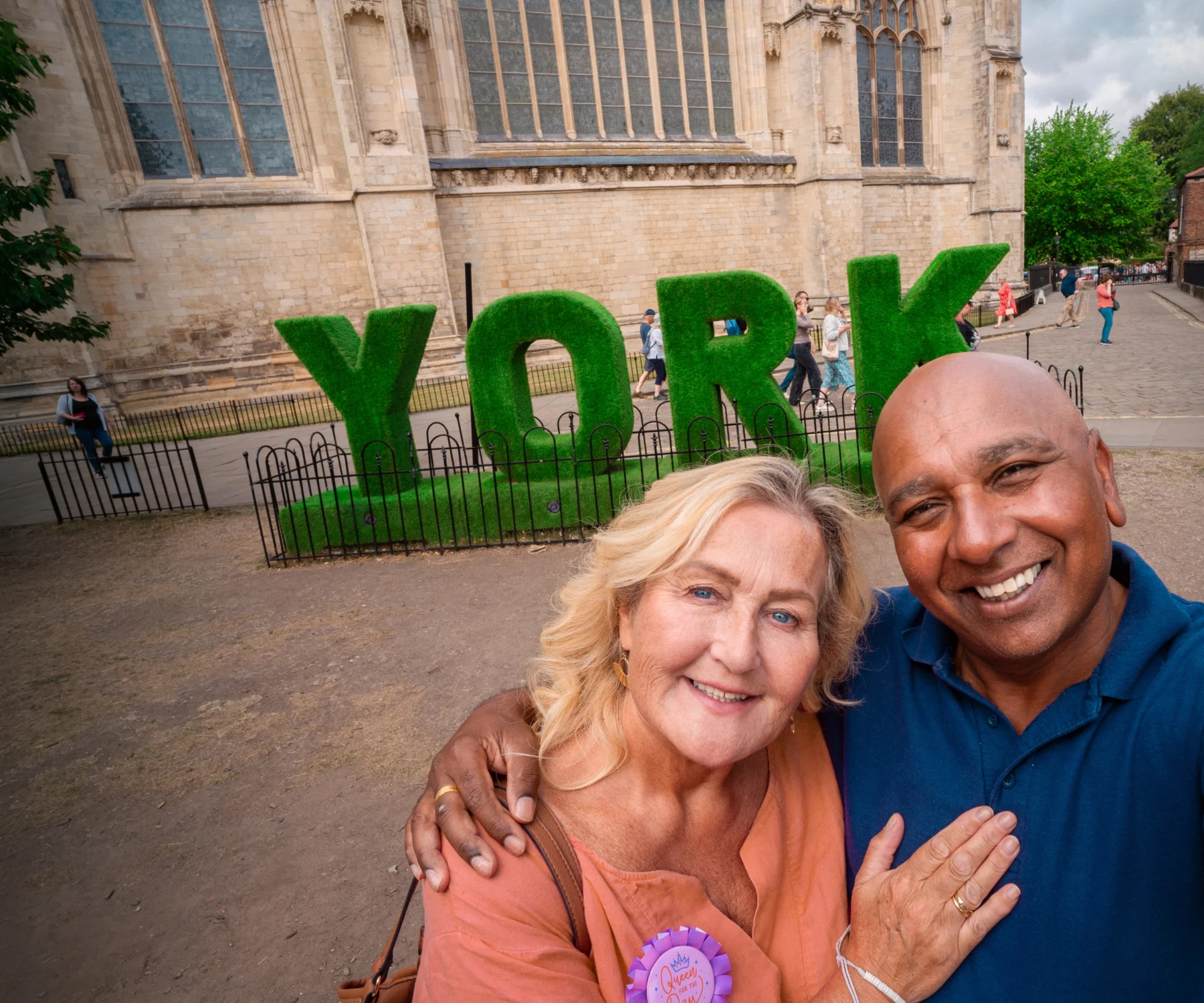 A man takes a selfie with his arm around a lady in front of a York sign