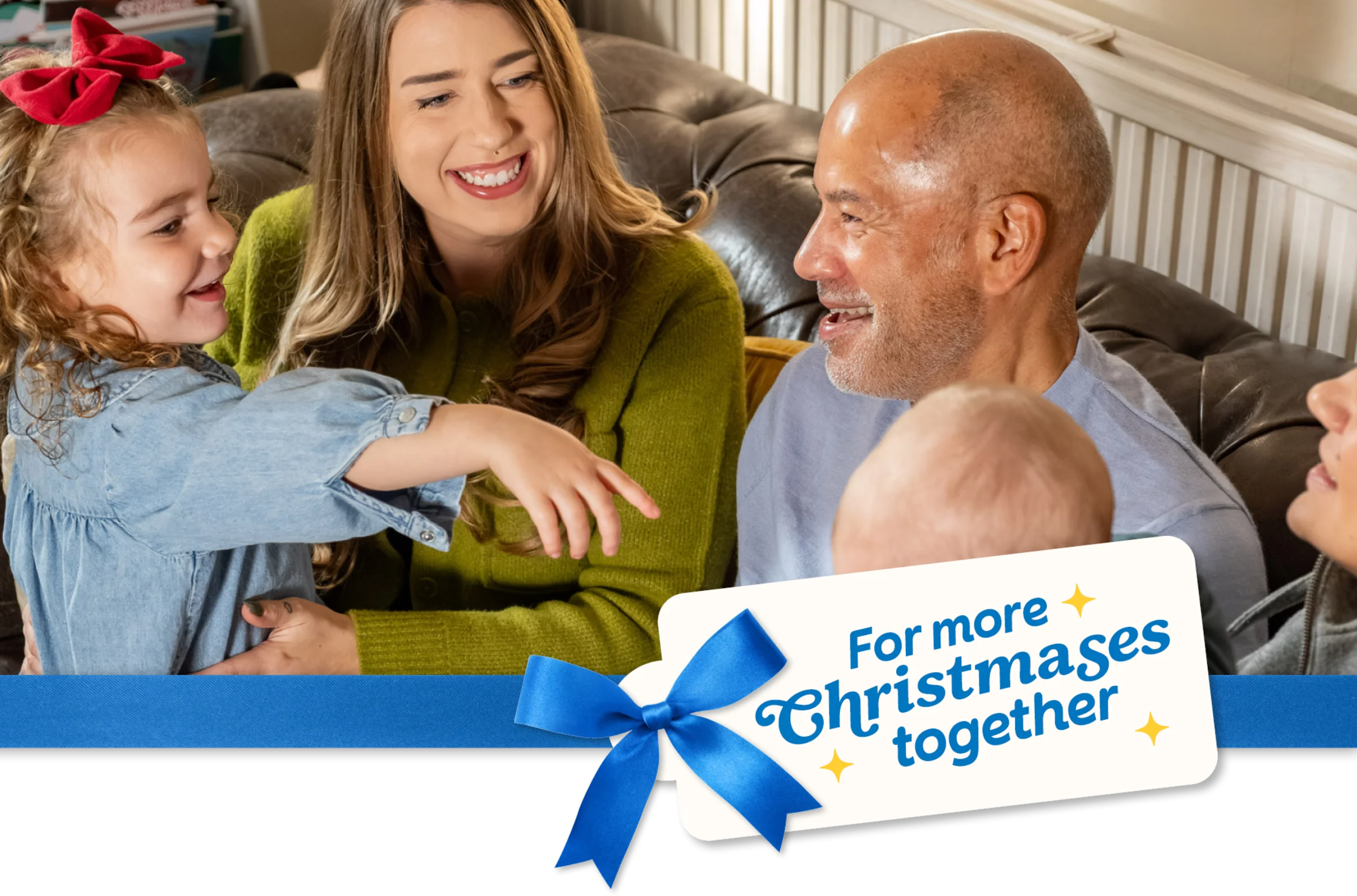 A family sit smiling and chatting together on a sofa