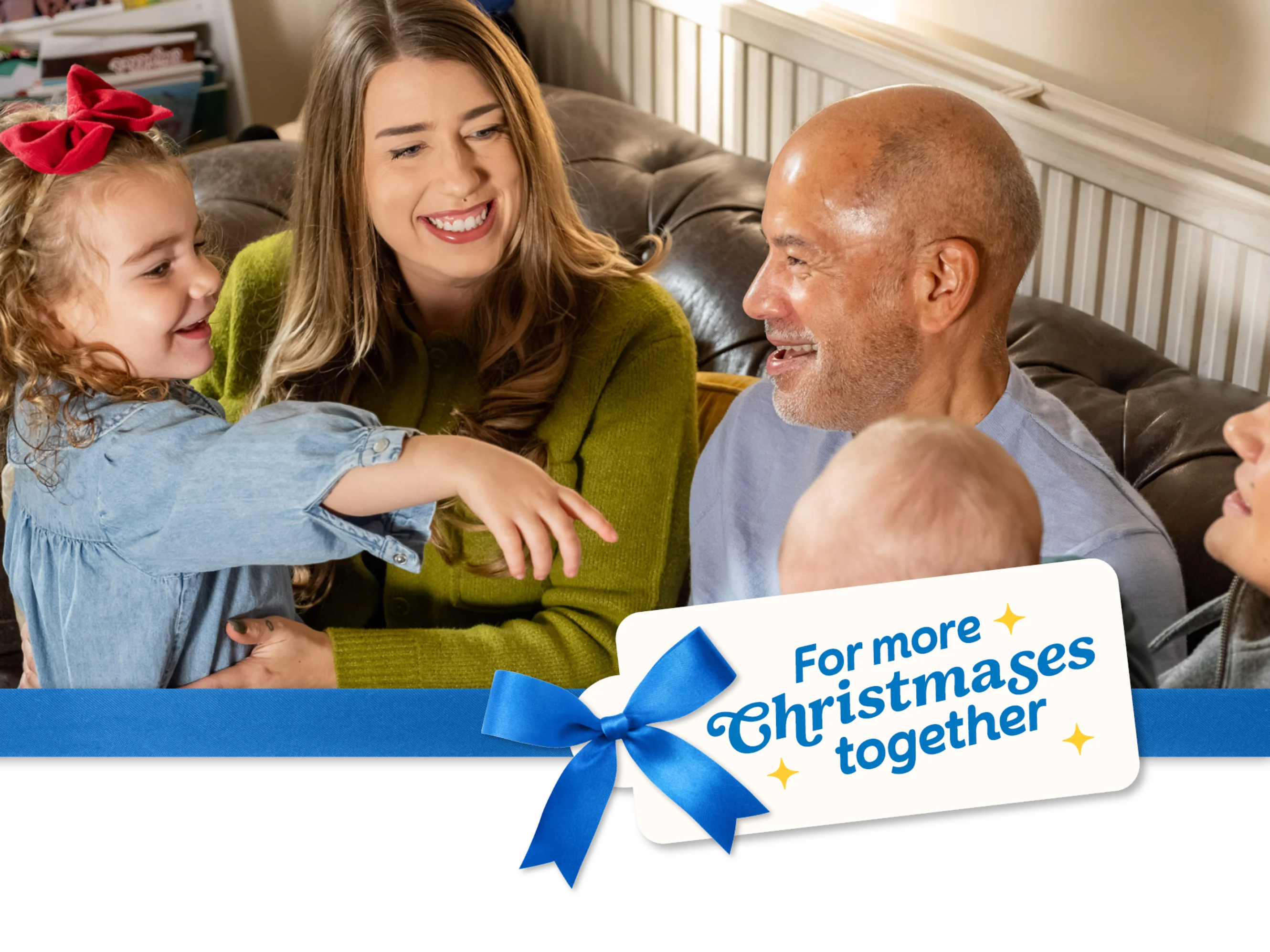 A family sit smiling and chatting together on a sofa