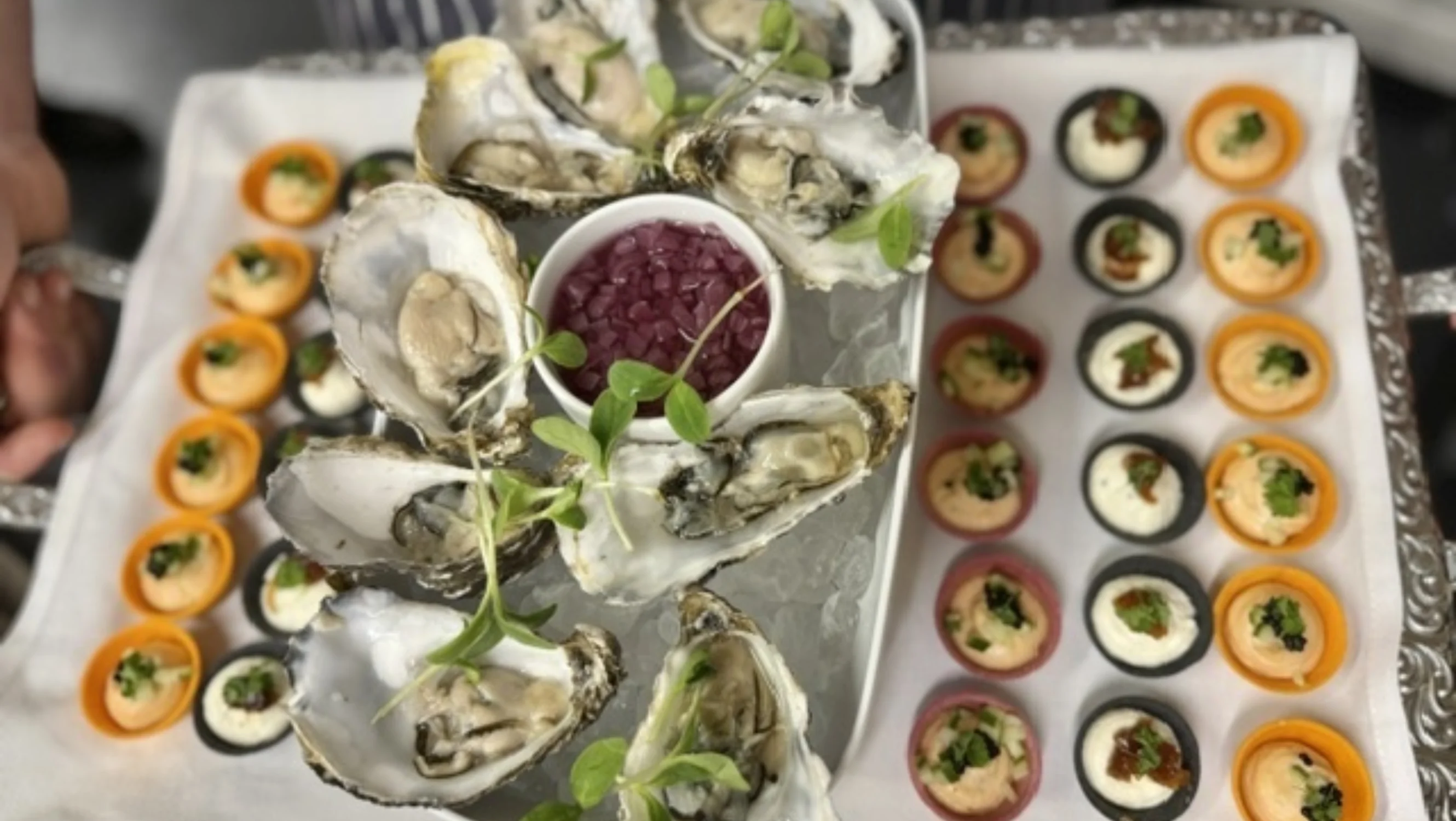 A platter of canapes including fresh oysters and garnish