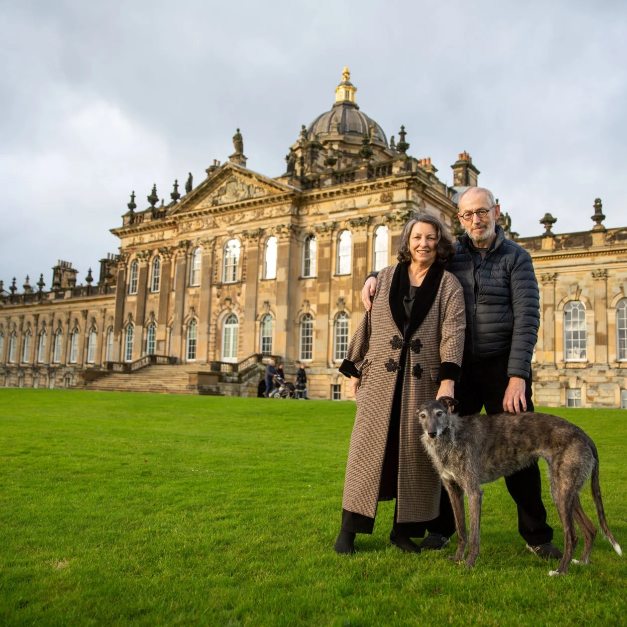 A woman, man and dog stand in front of Castle Howard