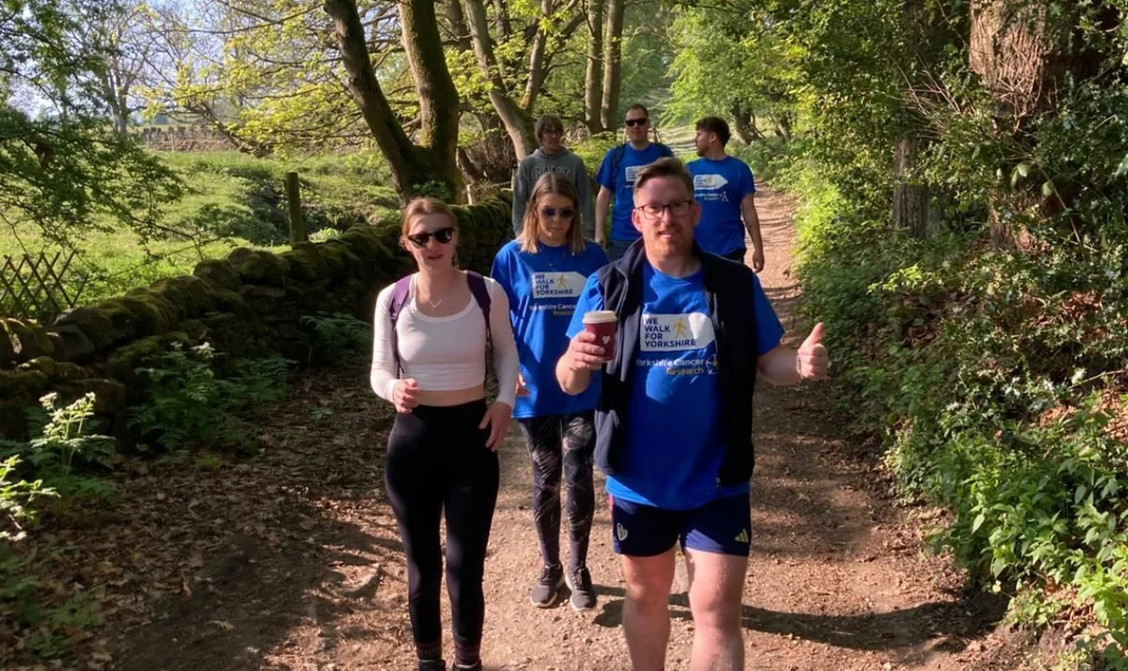 A group of people walking on a sunny wooded path