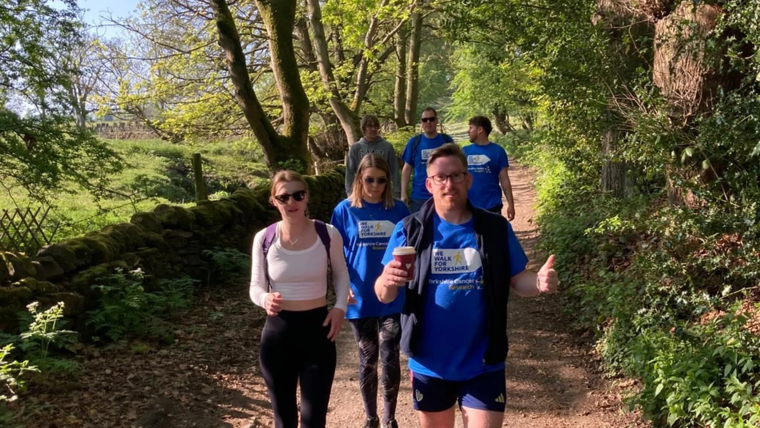 A group of people walk on a wooded path