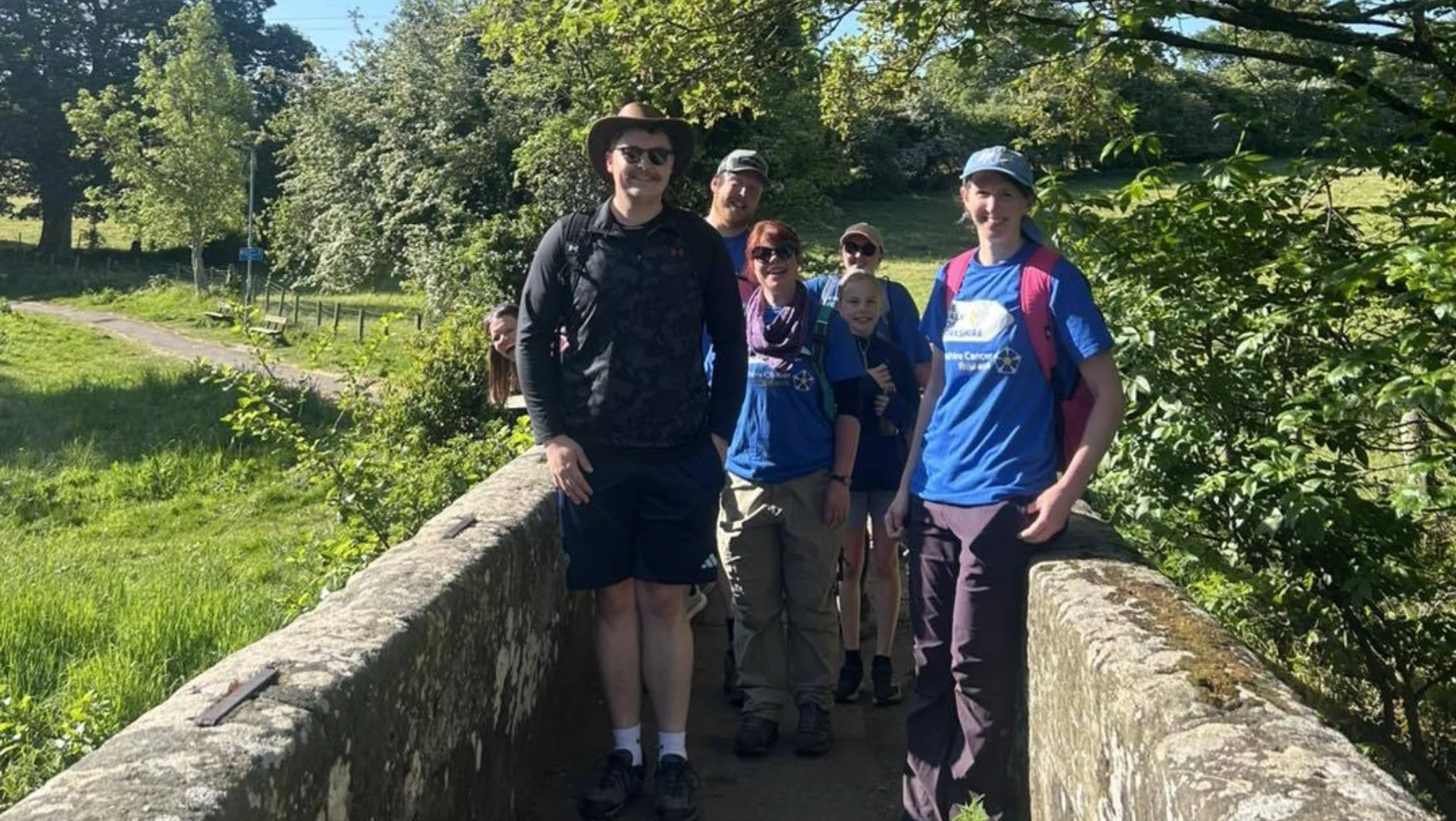 A group of people stand on a bridge in the sunshine