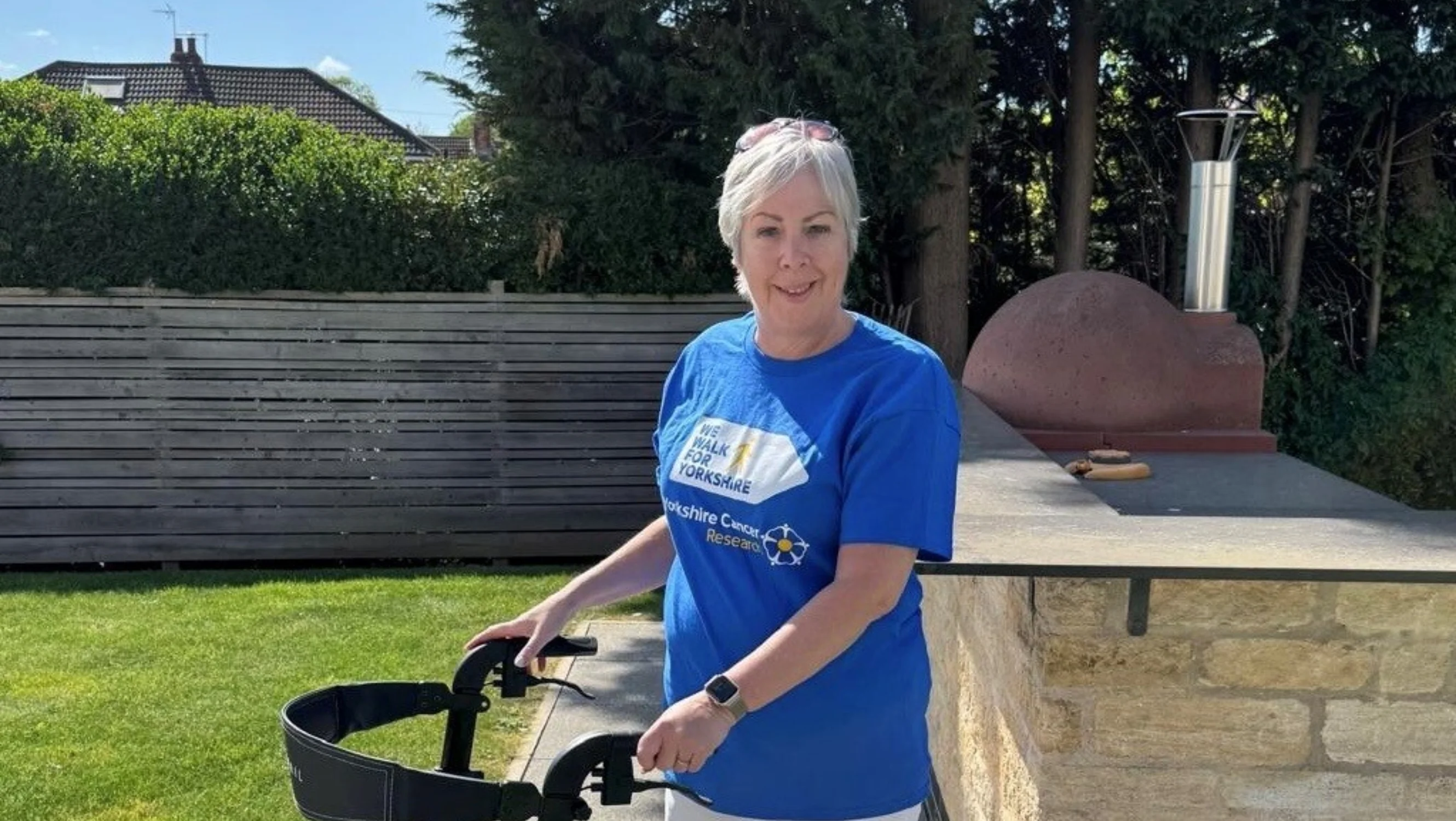 A lady stood on a garden patio with a walking aid