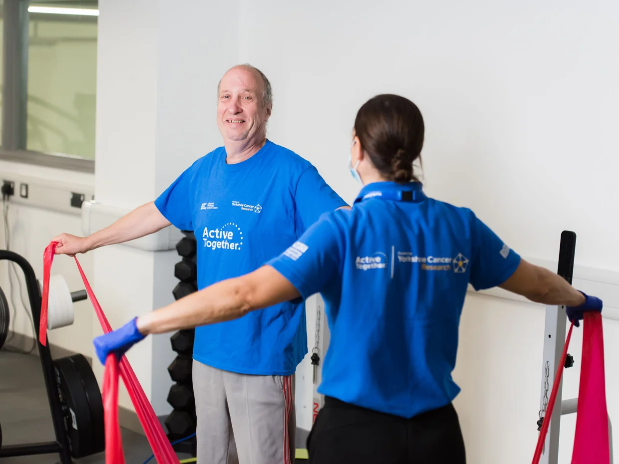 A patient using resistance resistance bands standing opposite an exercise specialist
