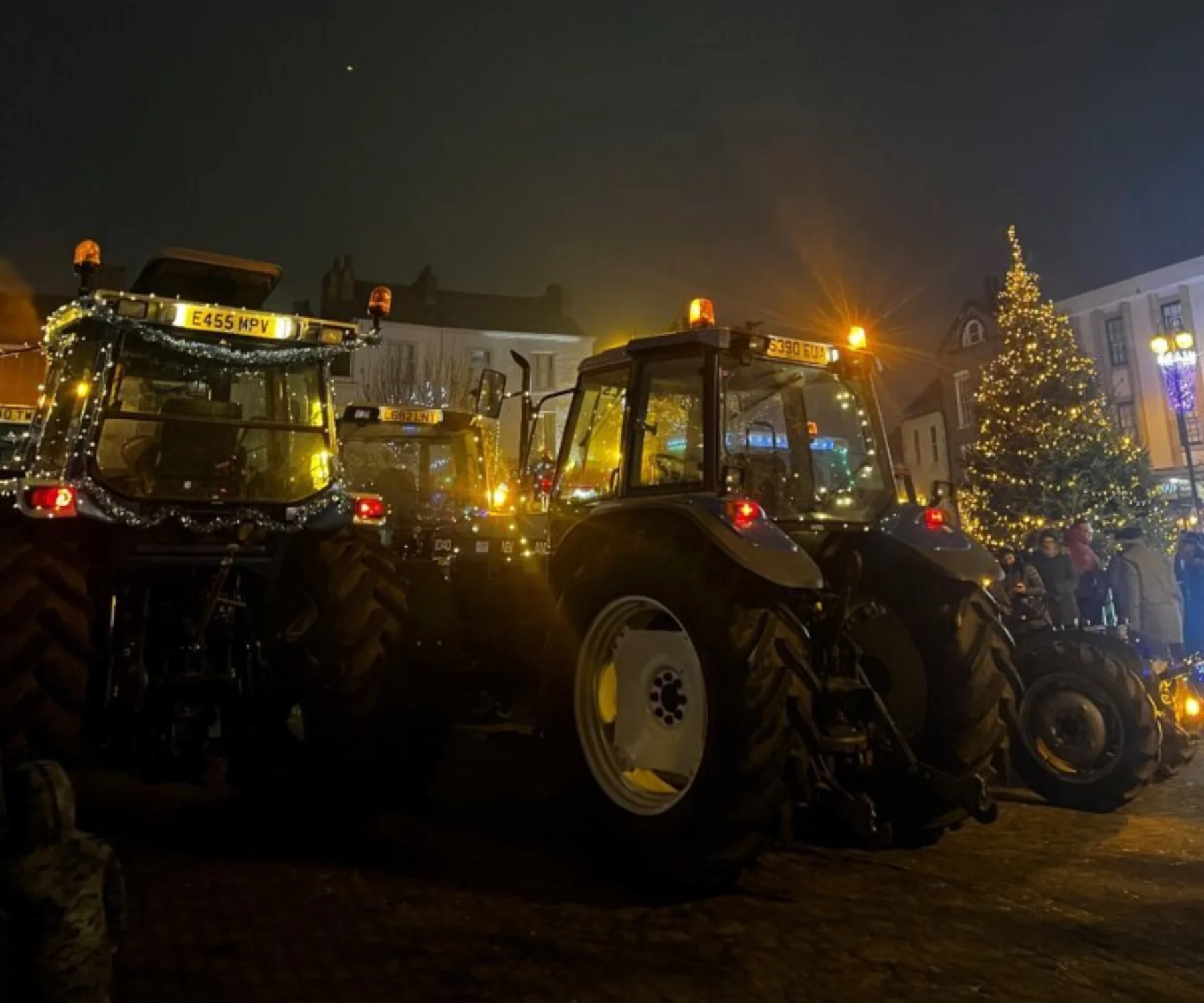 2 Tractors decorated in Christmas lights on a dark winter night