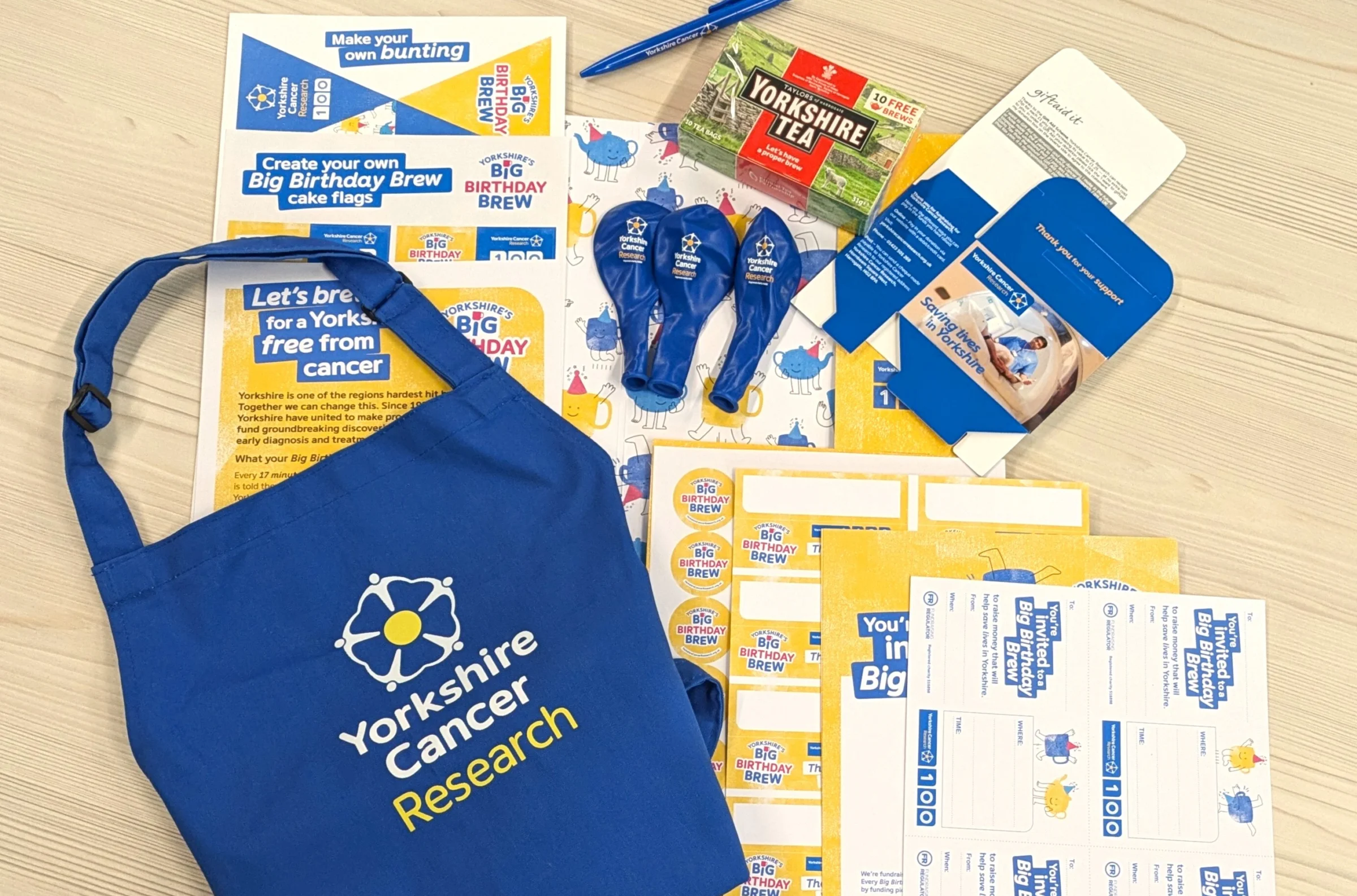 Collection of items including a box of Yorkshire Tea, balloons, bunting, posters, pen and various print items.