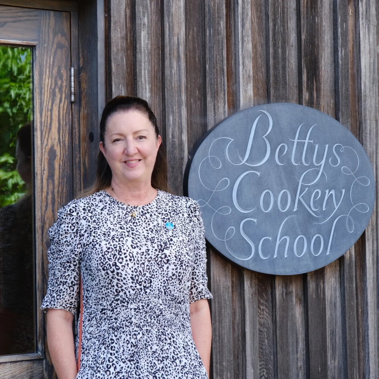 A lady stands in front of Bettys Cookery School