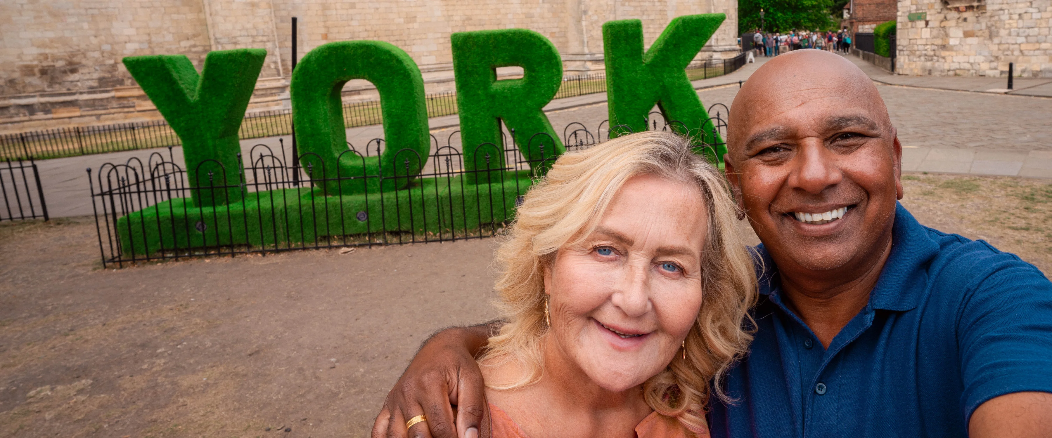 Julie and partner, stars of the Yorkshire Cancer Research advert, stand in front of a hedge sculpture which says York