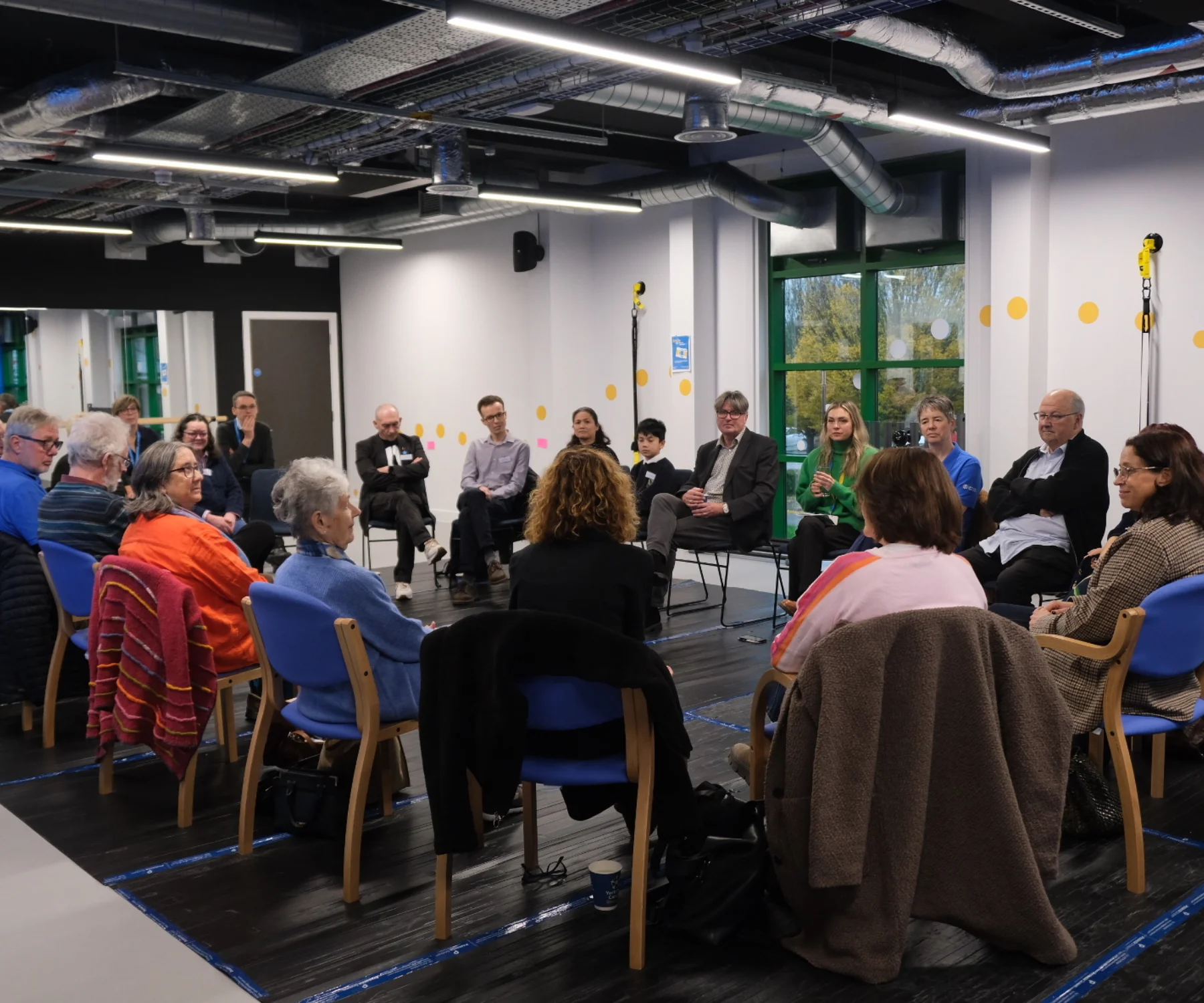 A group of people sit in a large circle in discussion