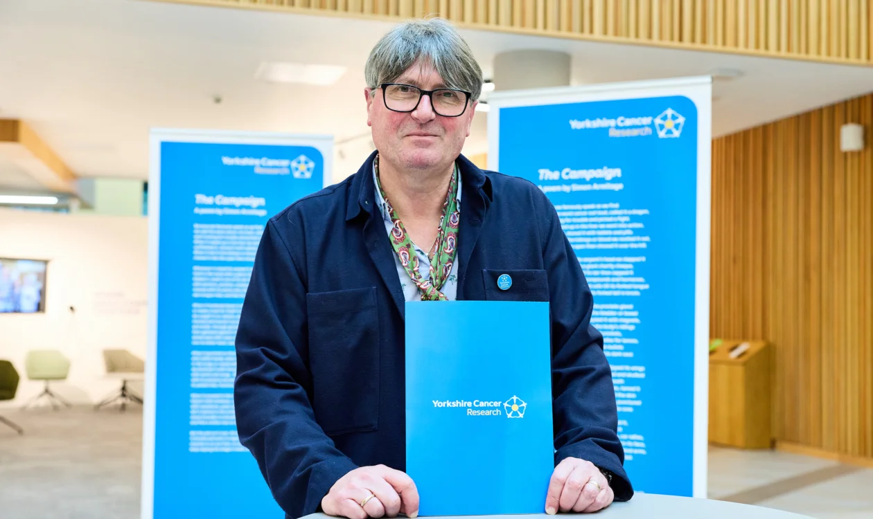 Poet Laureate Simon Armitage stands in front of large printouts of his poem, "The Campaign"